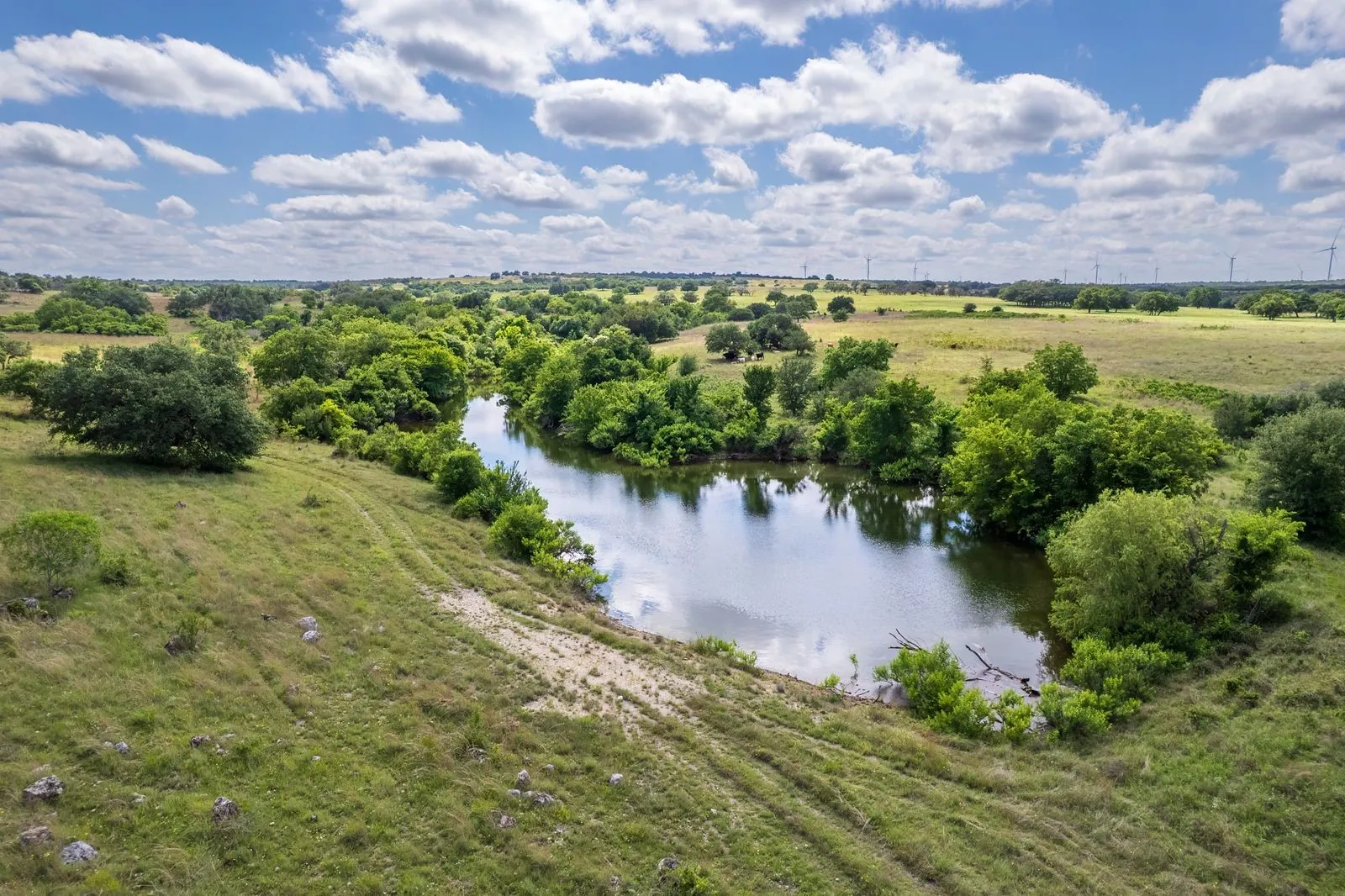 Expansive natural landscape featuring a winding waterway, lush green foliage, and open grassland