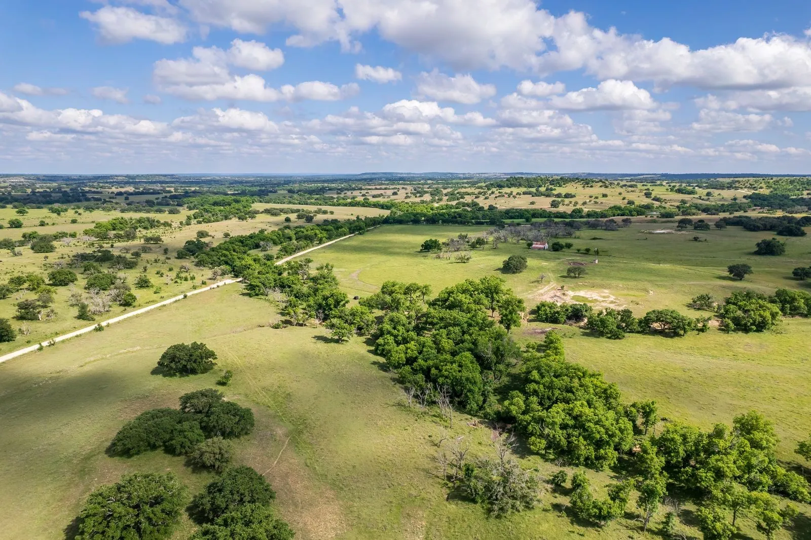 Expansive rural landscape featuring rolling green terrain and mature trees