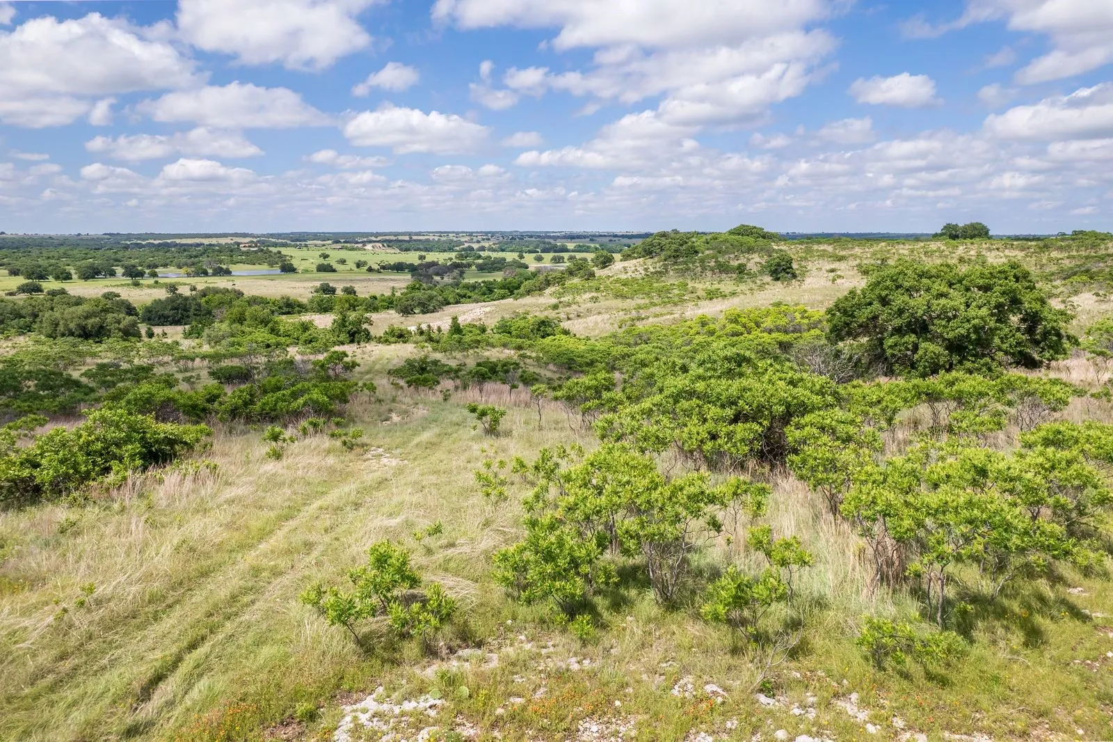 Expansive undeveloped land featuring varied topography, natural vegetation, and distant tree lines