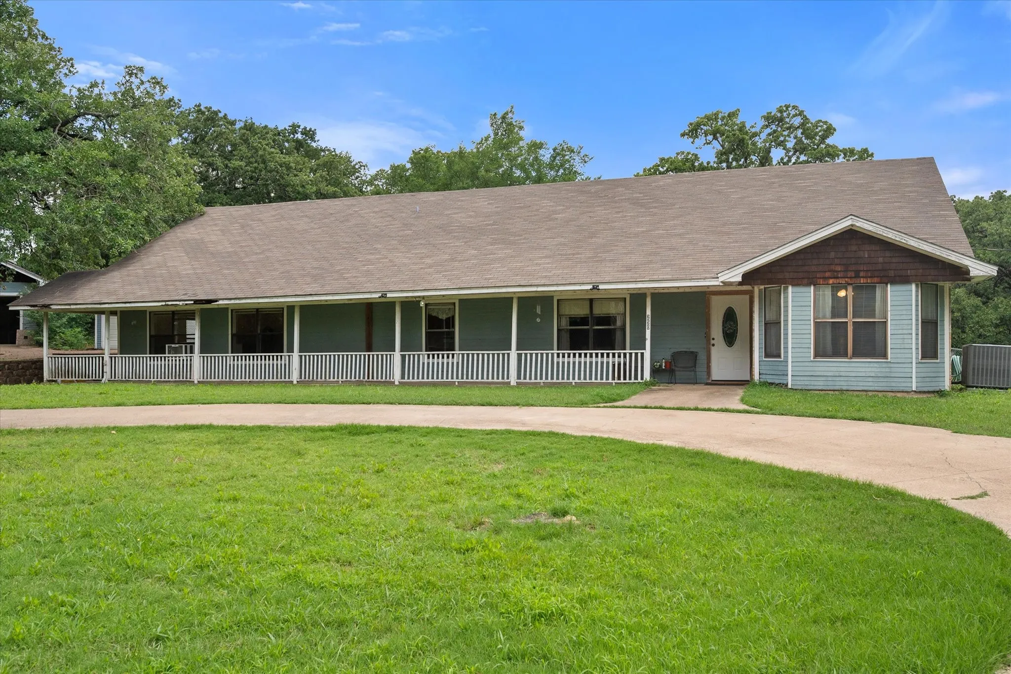 Front exterior view featuring a covered porch, large lawn, and classic ranch-style curb appeal in Corsicana.