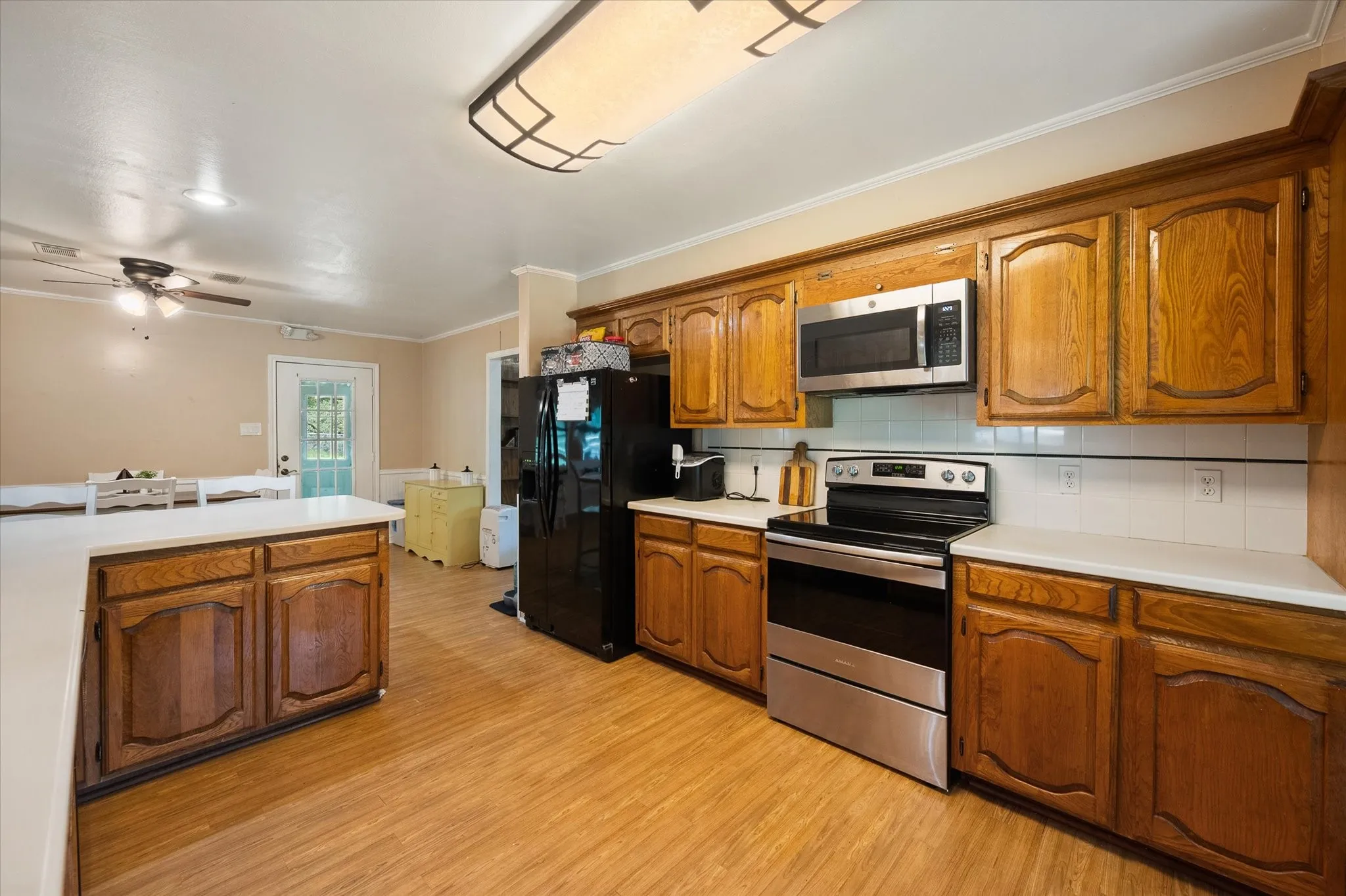 Corsicana kitchen features wood cabinetry, electric range, microwave, and views of the front porch.