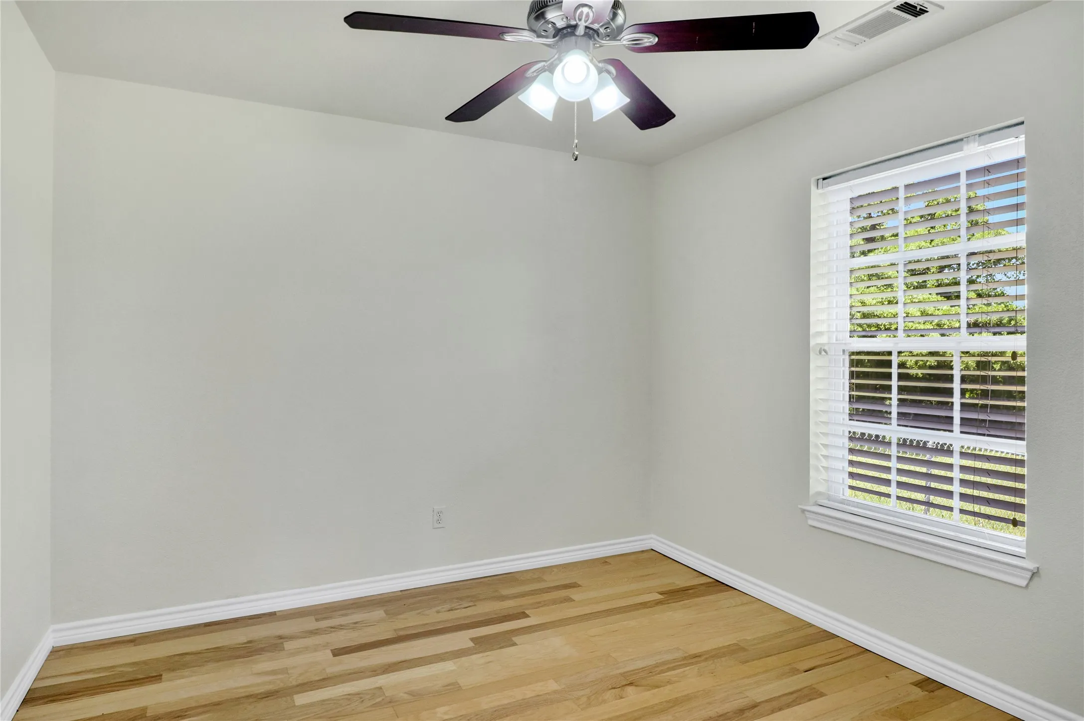 Interior space with light-toned walls, wood-finish flooring, and white baseboards