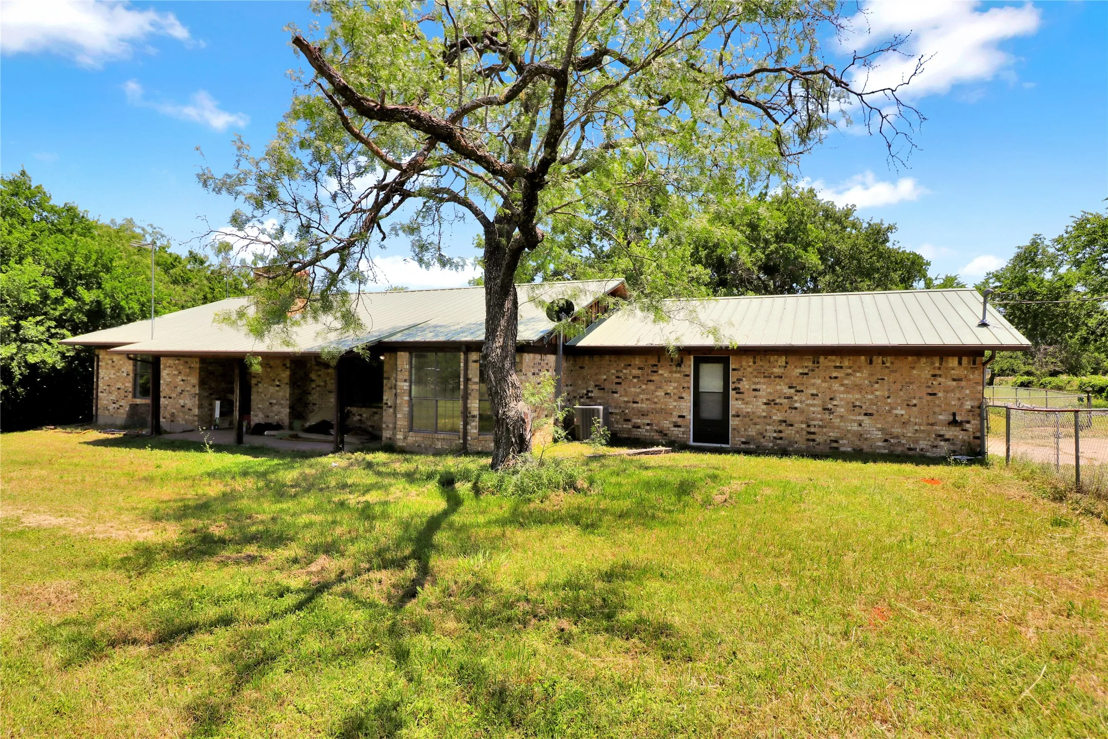 Brick exterior ranch-style residence featuring a metal roof and large front windows