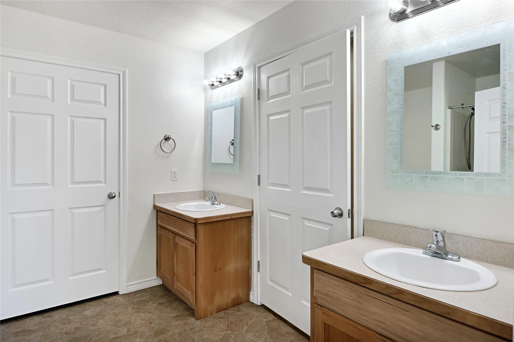 Dual vanity bathroom featuring light wood-finish cabinetry and neutral countertops