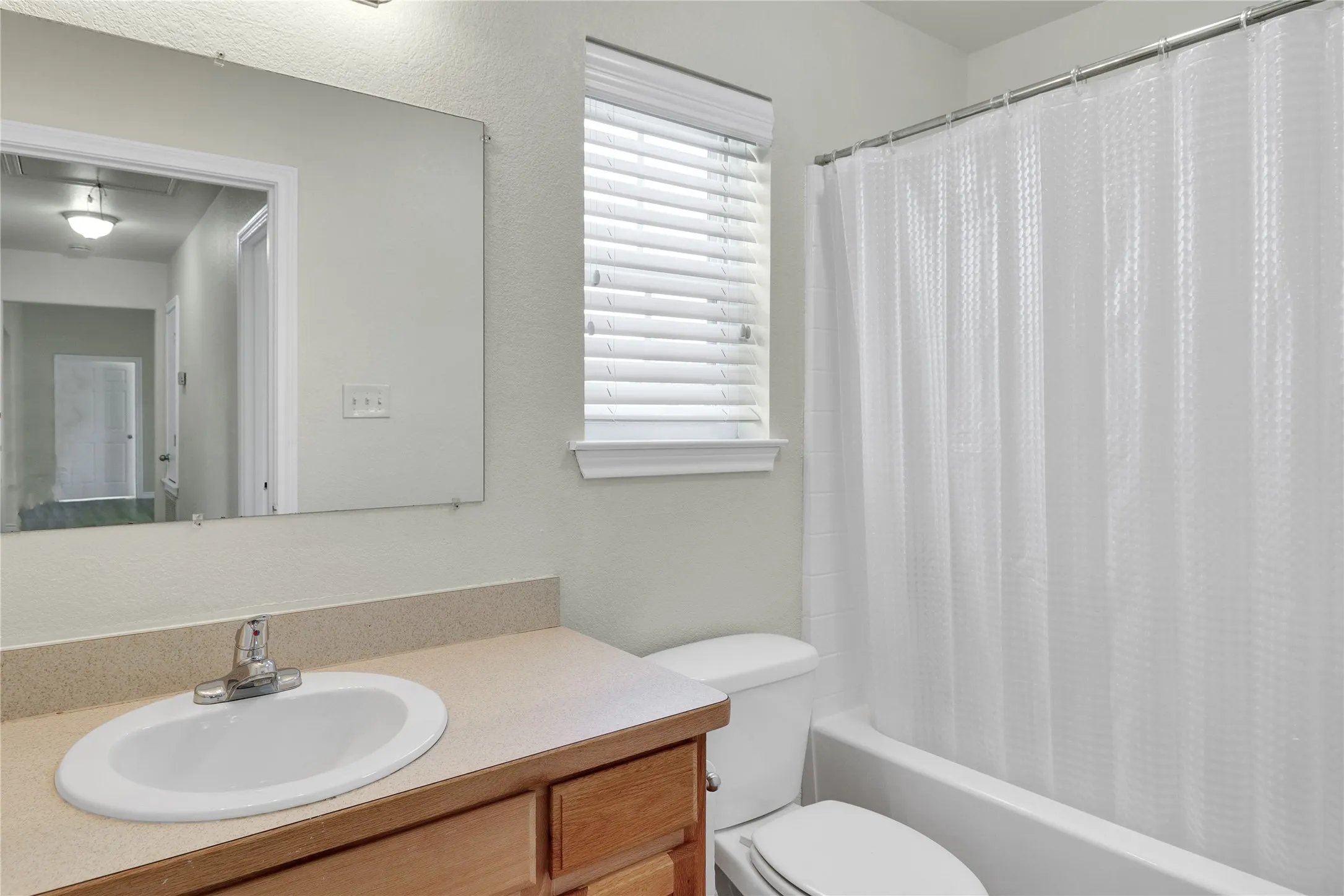Bathroom featuring a vanity with wood-finish cabinetry, an oval undermount sink, and a light-toned countertop