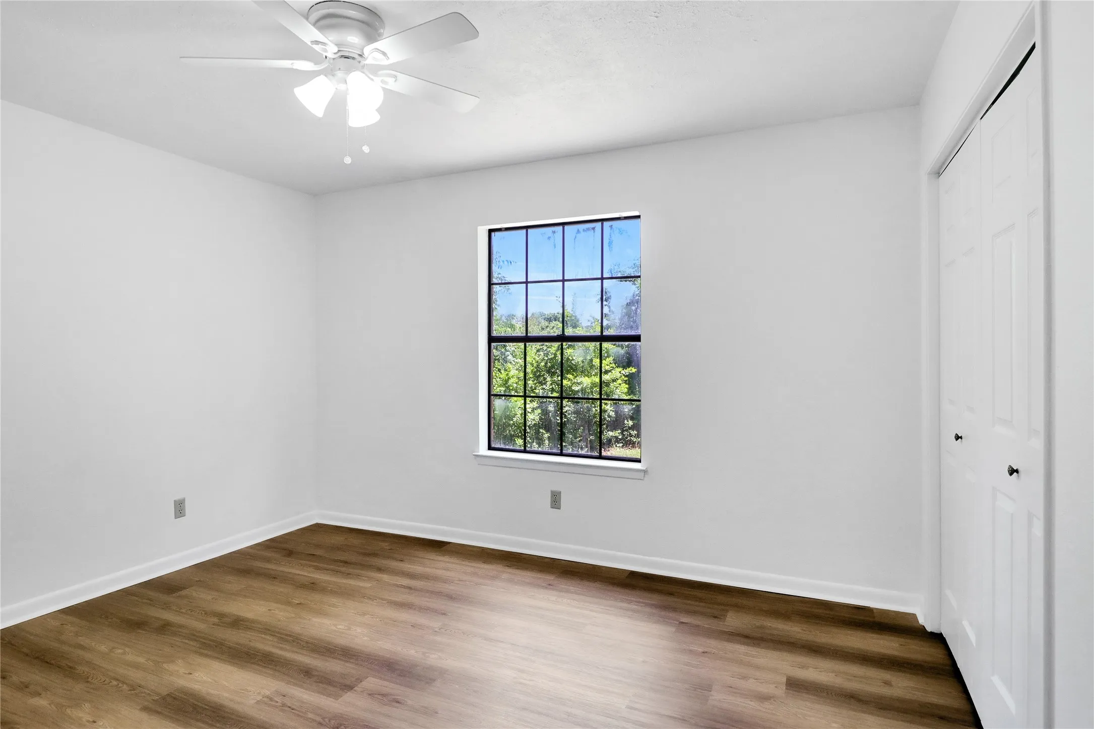 White walls, wood-finish flooring, and white ceiling fan