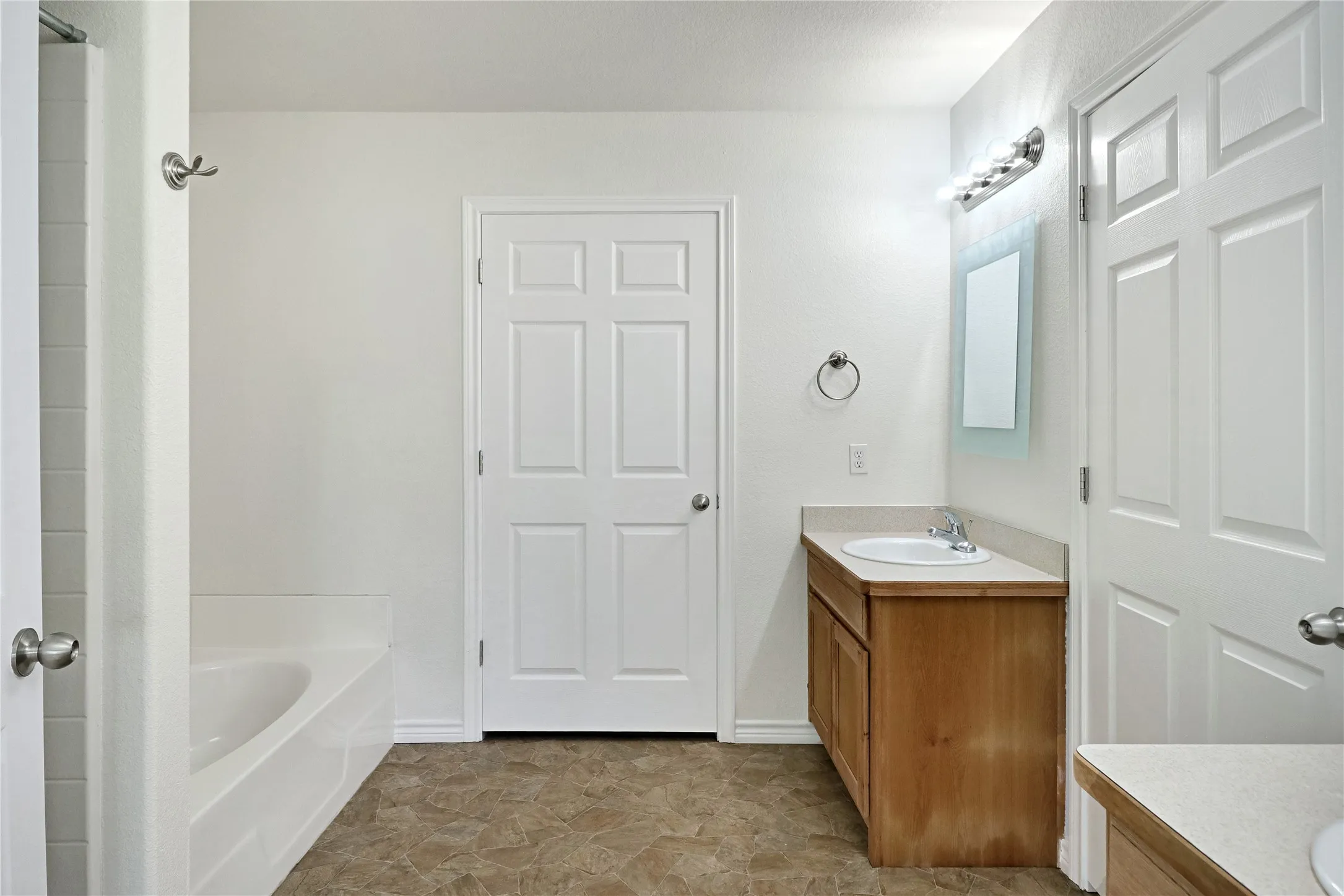 Bathroom featuring a single vanity with wood-finish cabinetry and a light-colored countertop