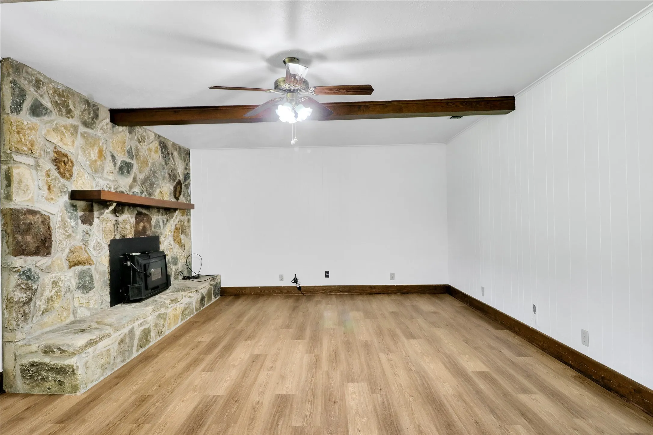 Spacious room featuring a prominent floor-to-ceiling stone fireplace with a wood mantel