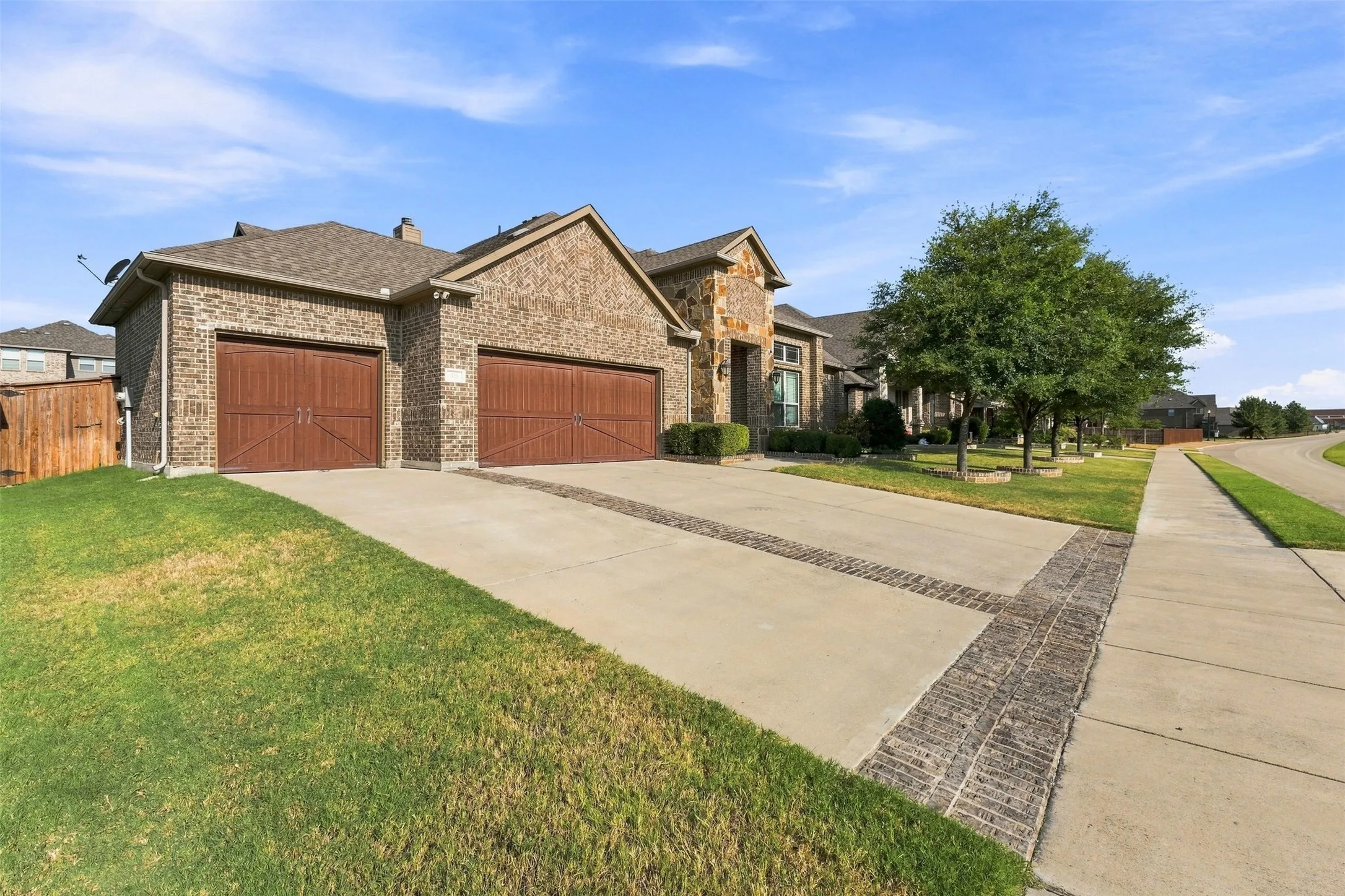 Striking stone and brick exterior with dual three-car garage doors finished in rich red-brown tones