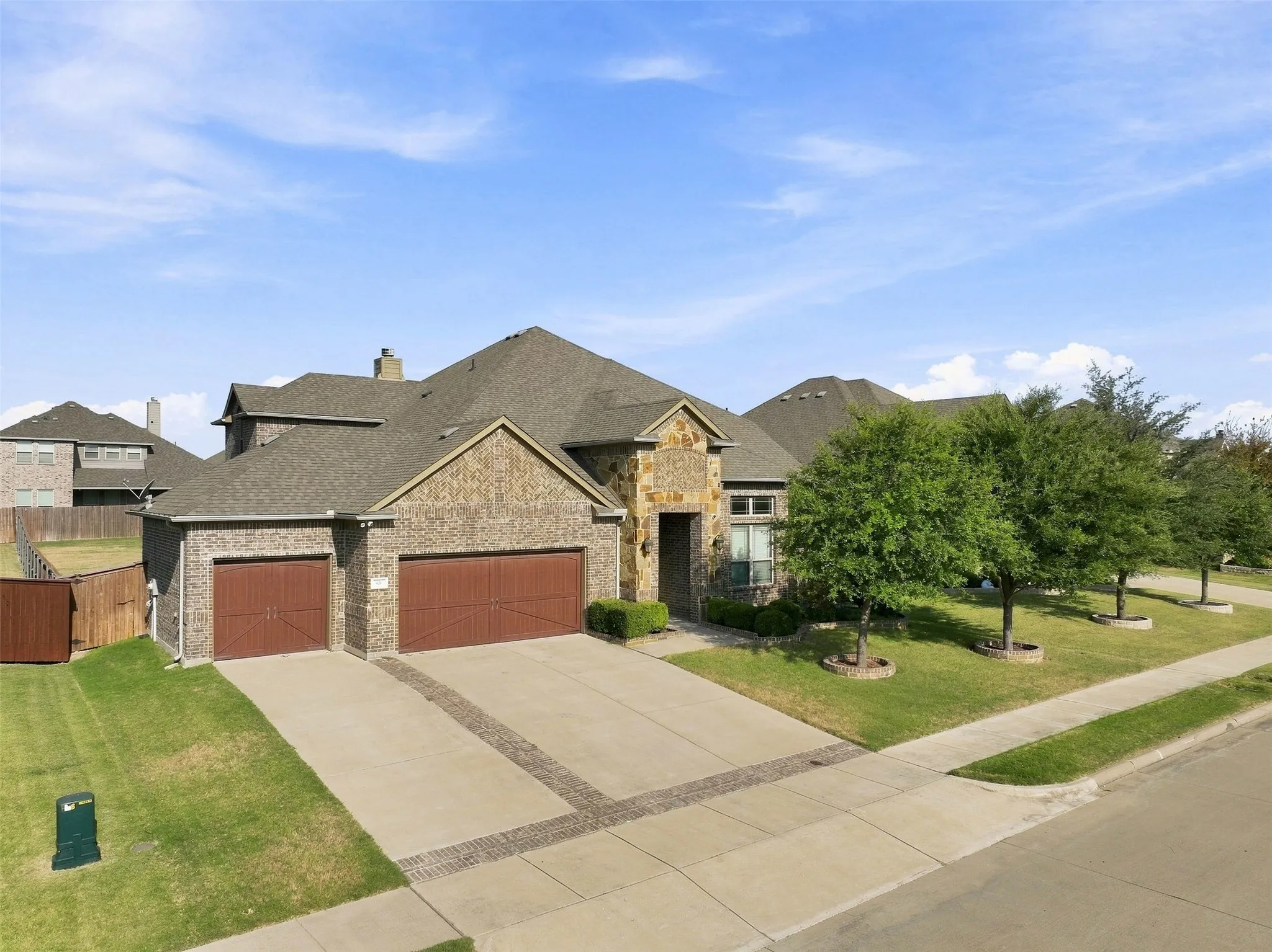 Elegant stone and brick exterior with three-car garage featuring rich red panel doors
