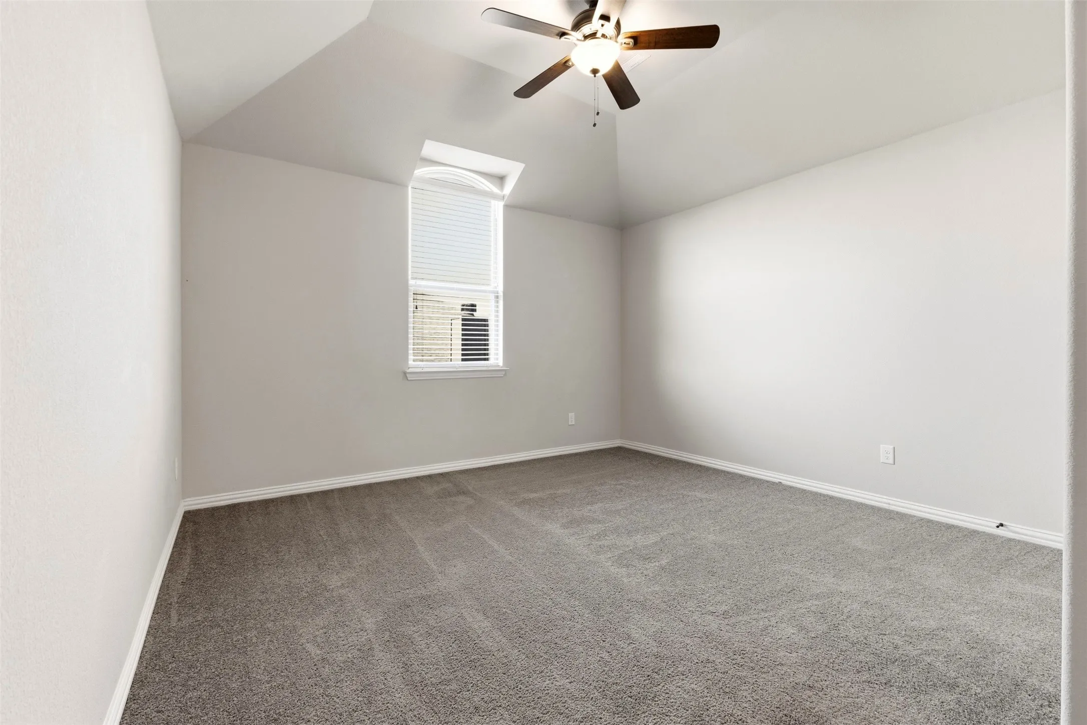 Vaulted ceiling with a ceiling fan, neutral wall paint, gray carpeting, and a window with blinds