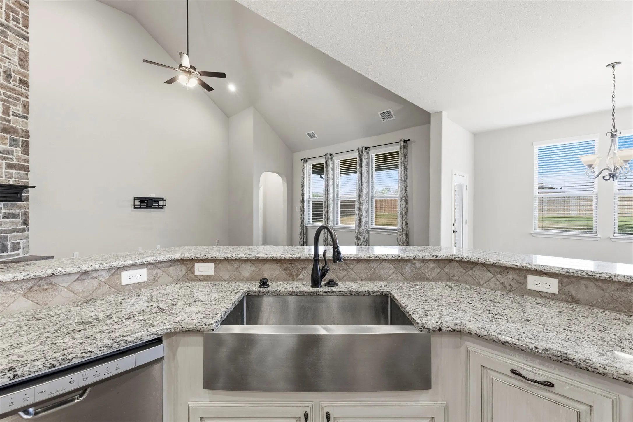 Kitchen featuring granite countertops, a stainless steel farmhouse sink, and a tile backsplash