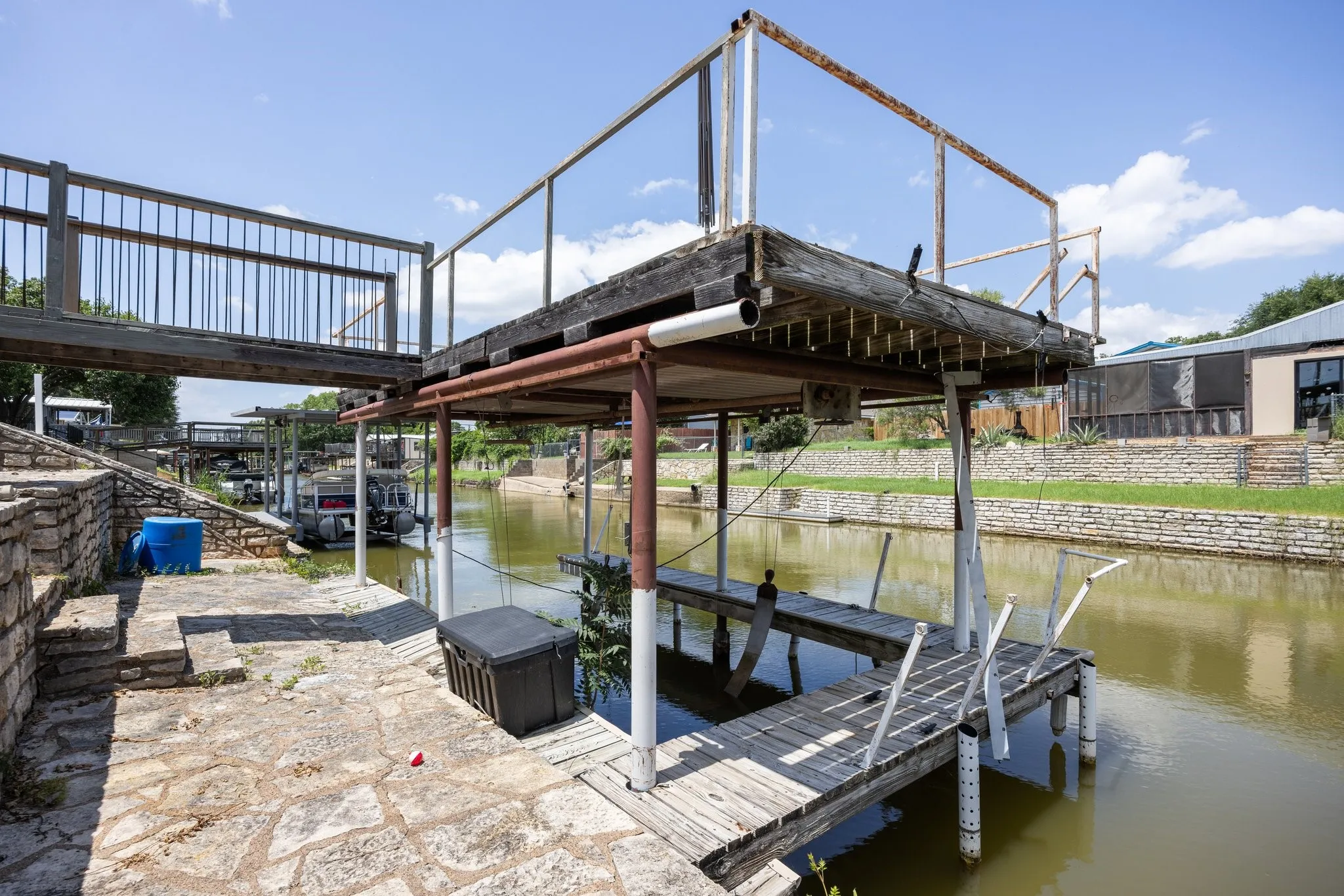 Private boat dock with overhead deck, featuring a flagstone patio and stone retaining walls