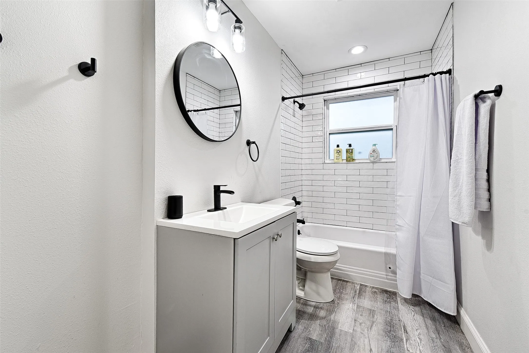 Full bathroom with wood-type flooring, vanity, toilet, and shower / tub combo with curtain