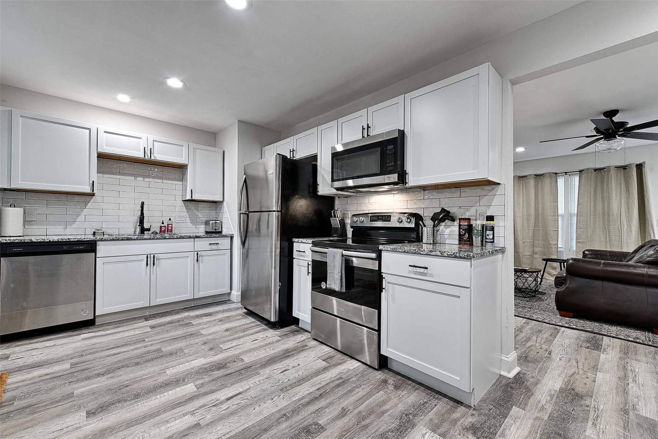 Kitchen featuring light wood-type flooring, white cabinets, and stainless steel appliances