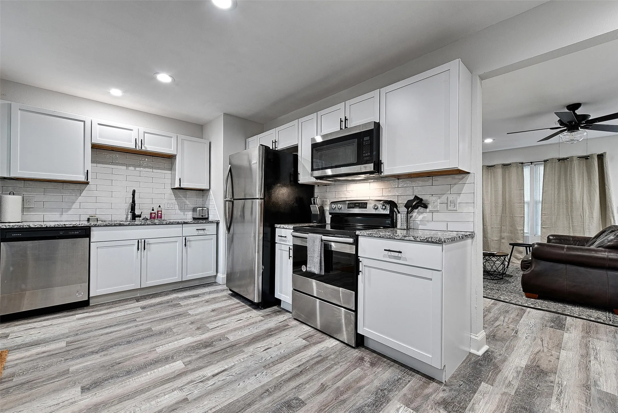 Kitchen with stainless steel appliances, light hardwood / wood-style floors, and white cabinetry