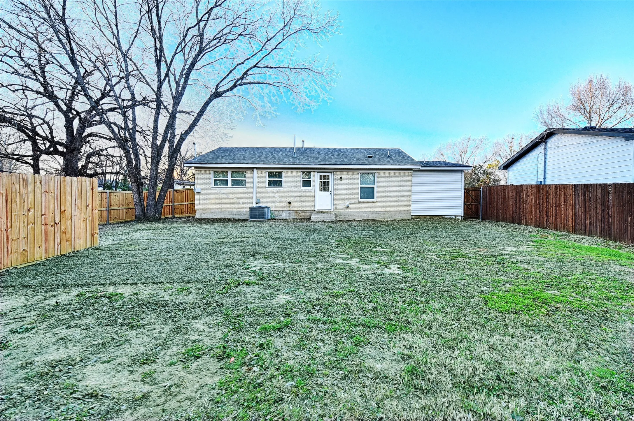 Rear view of house with central air condition unit and a lawn