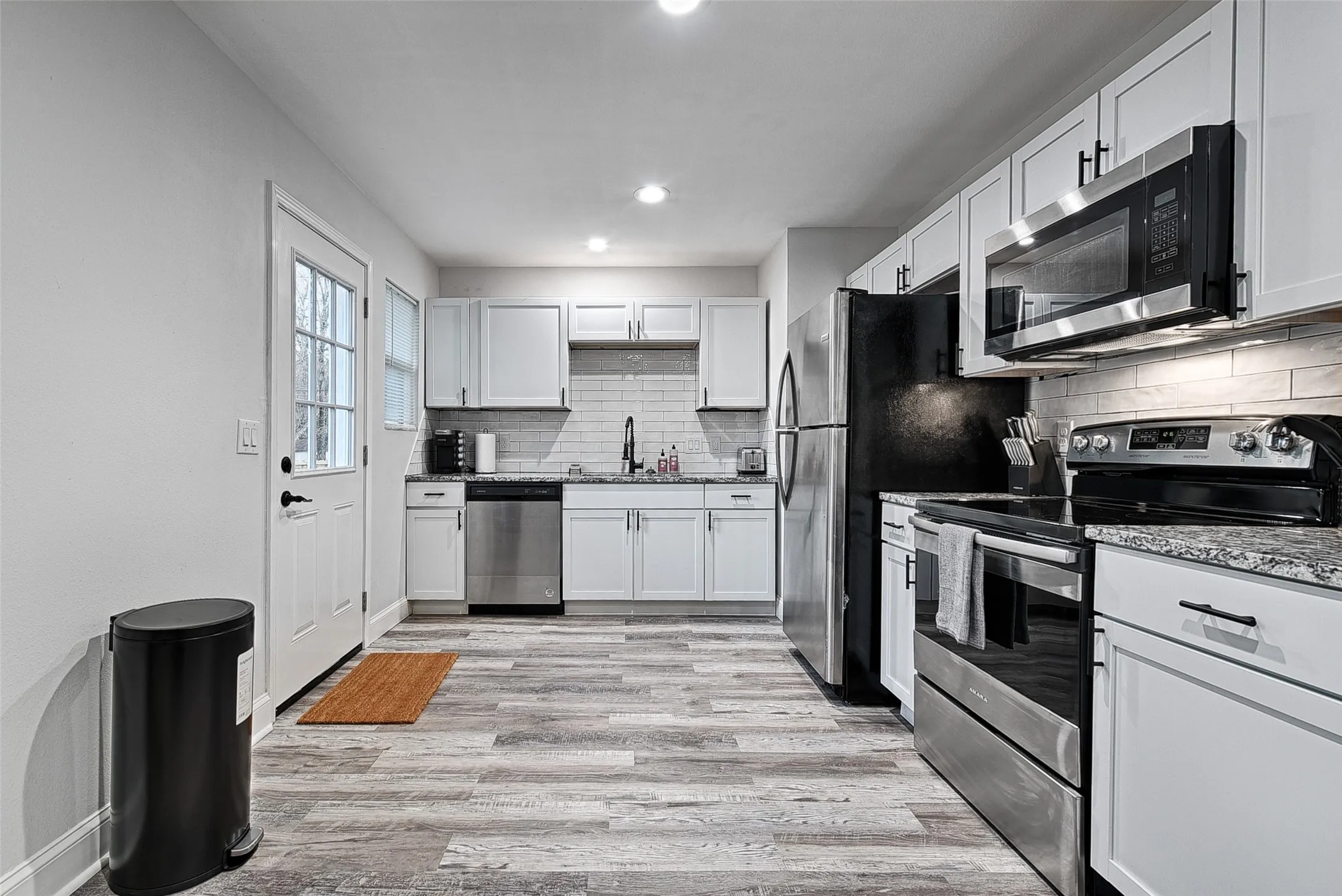 Kitchen featuring white cabinetry, decorative backsplash, appliances with stainless steel finishes, and light hardwood / wood-style flooring