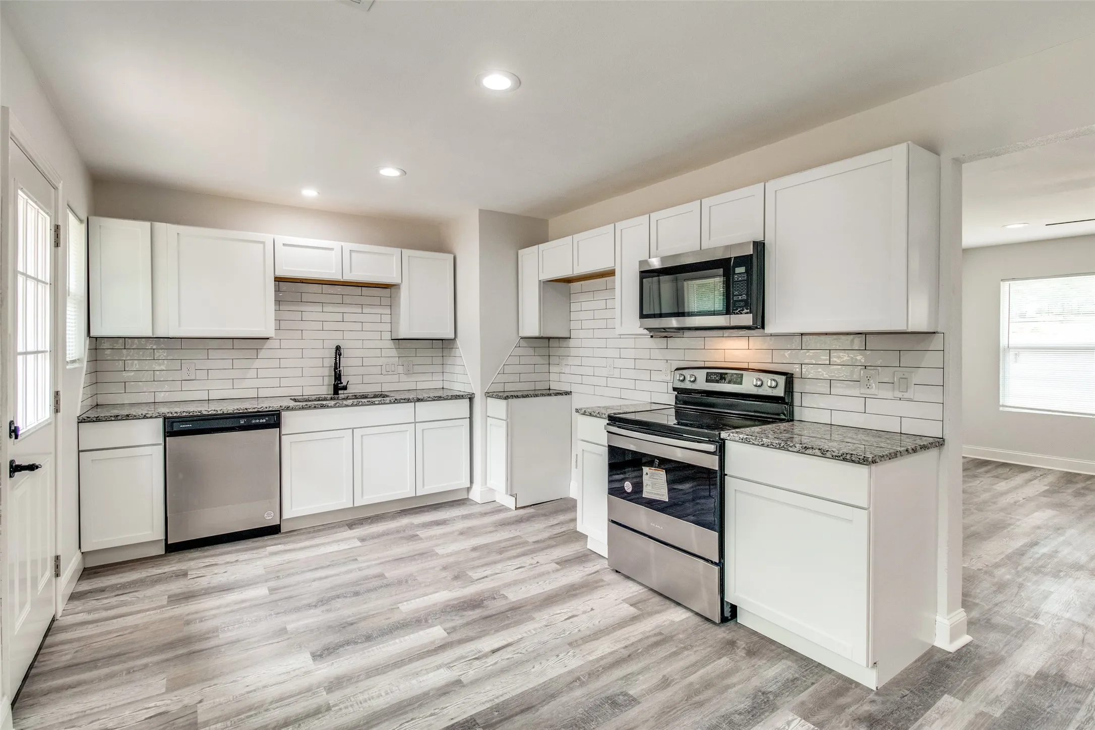 Kitchen with white cabinetry, light hardwood / wood-style floors, stainless steel appliances, and sink