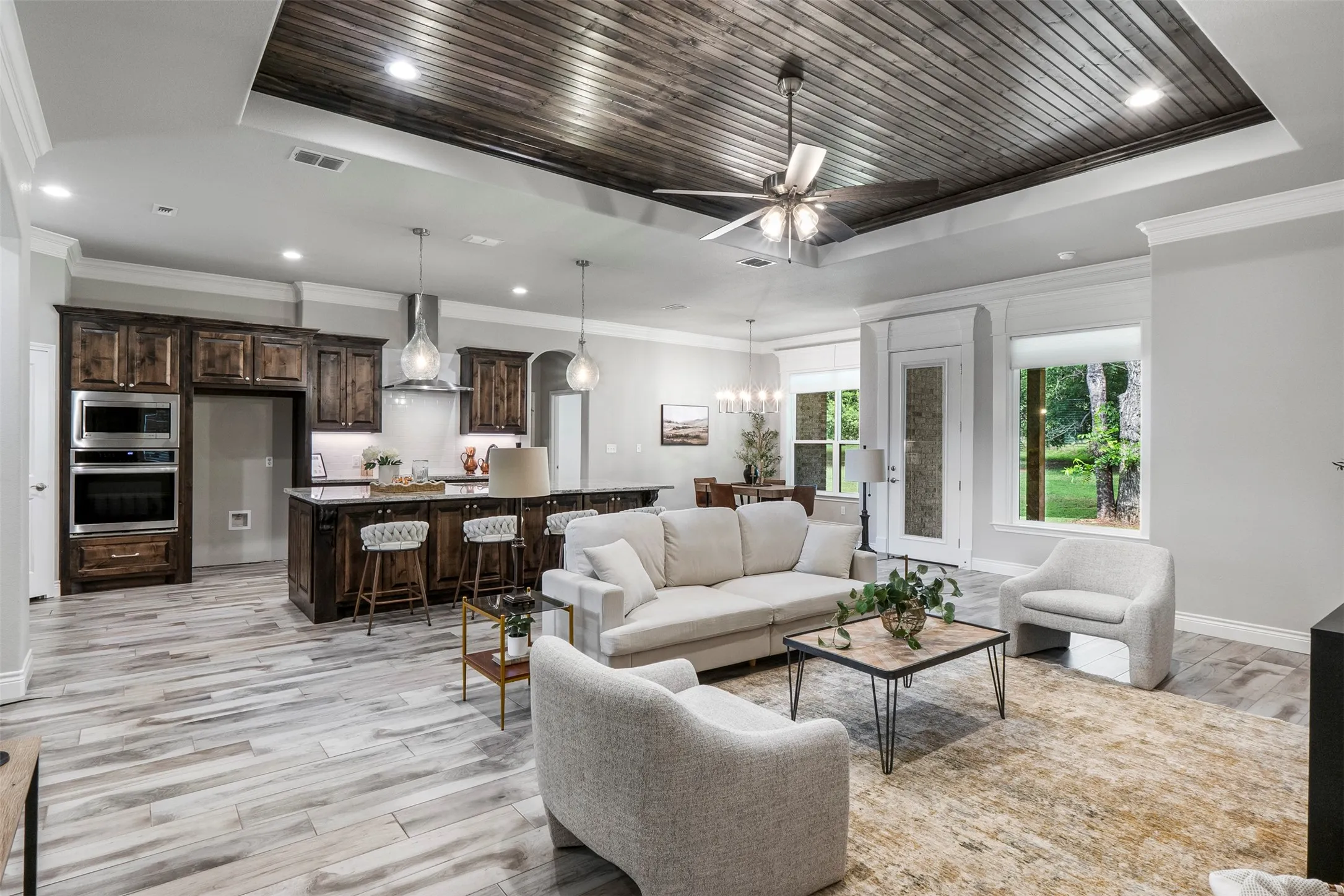 Spacious living room with exposed wood beam ceiling, abundant natural light and views toward the pecan orchard.
