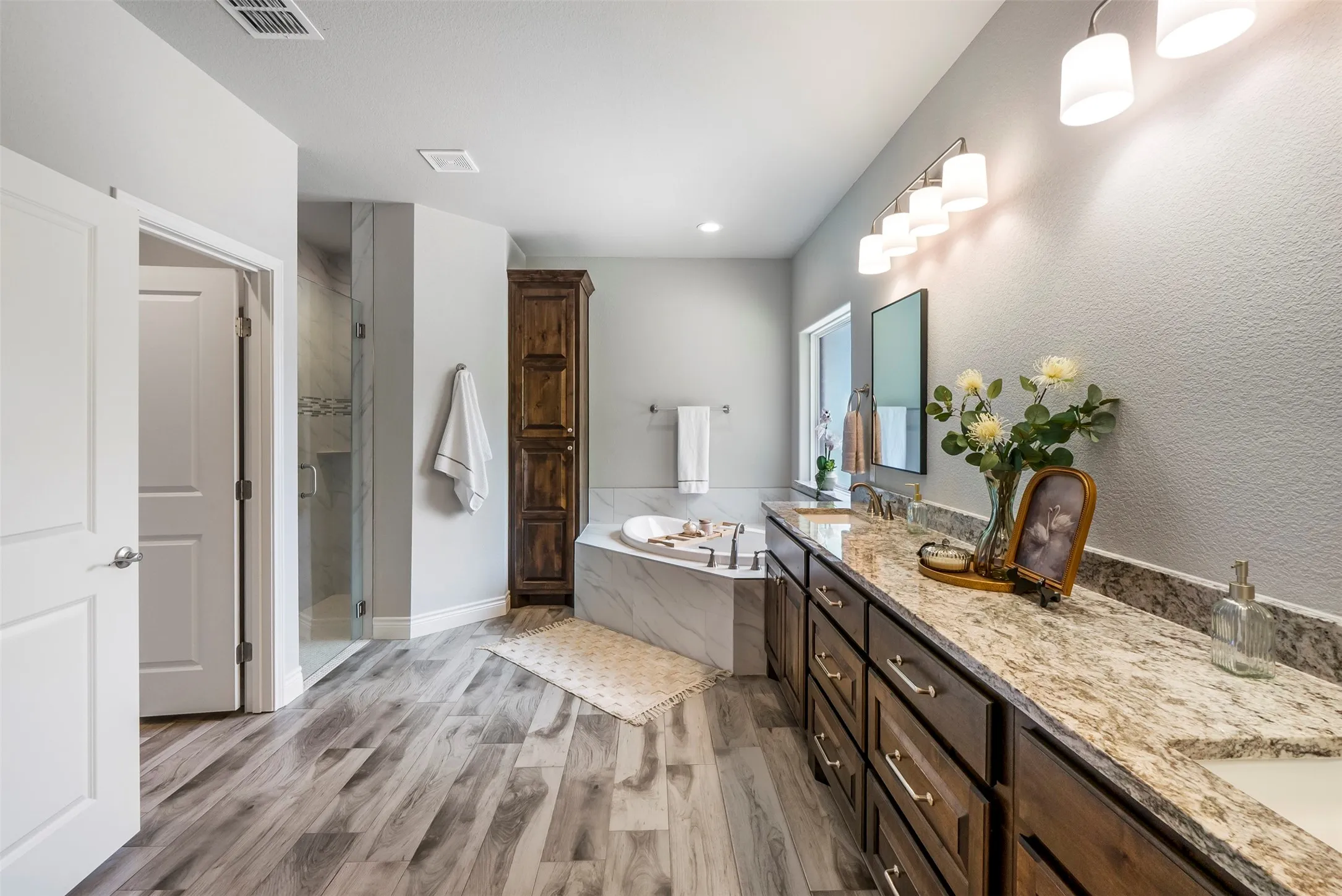Primary bathroom with dual vanities, soaking tub, oversized walk-in tiled shower and generous storage.