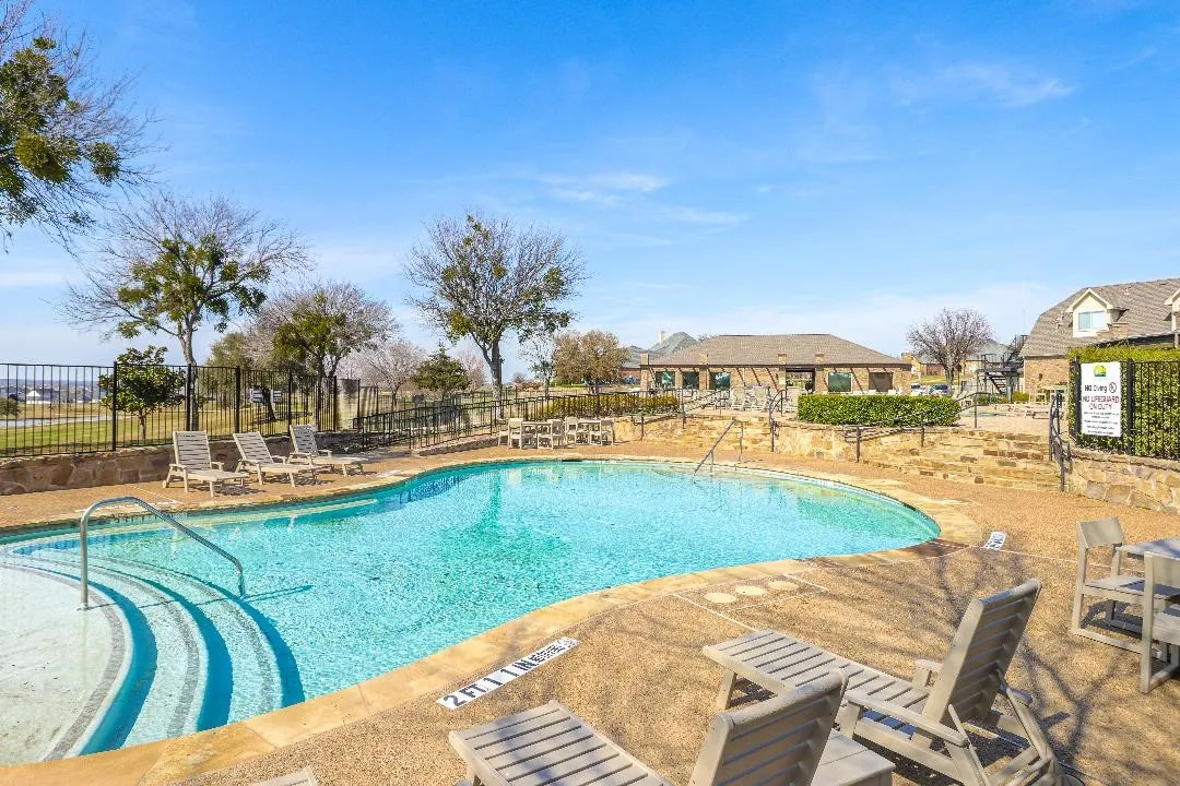 The community pool with tables and chairs to enjoy the day.