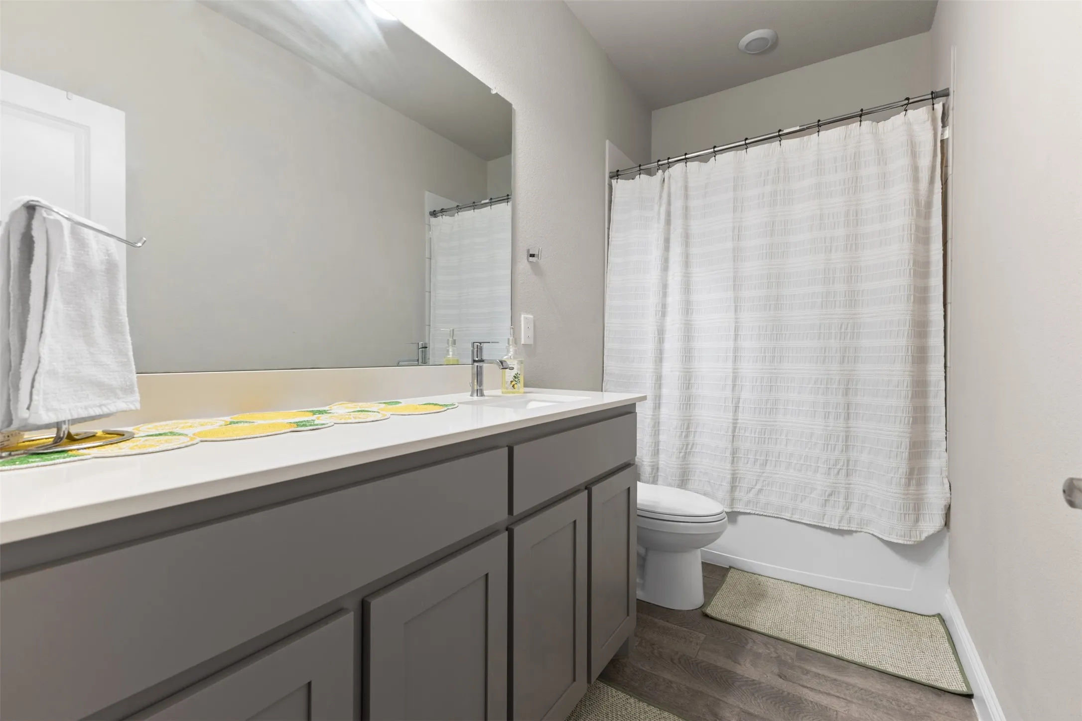 Bathroom featuring a vanity with a white countertop, gray cabinetry, and a large mirror