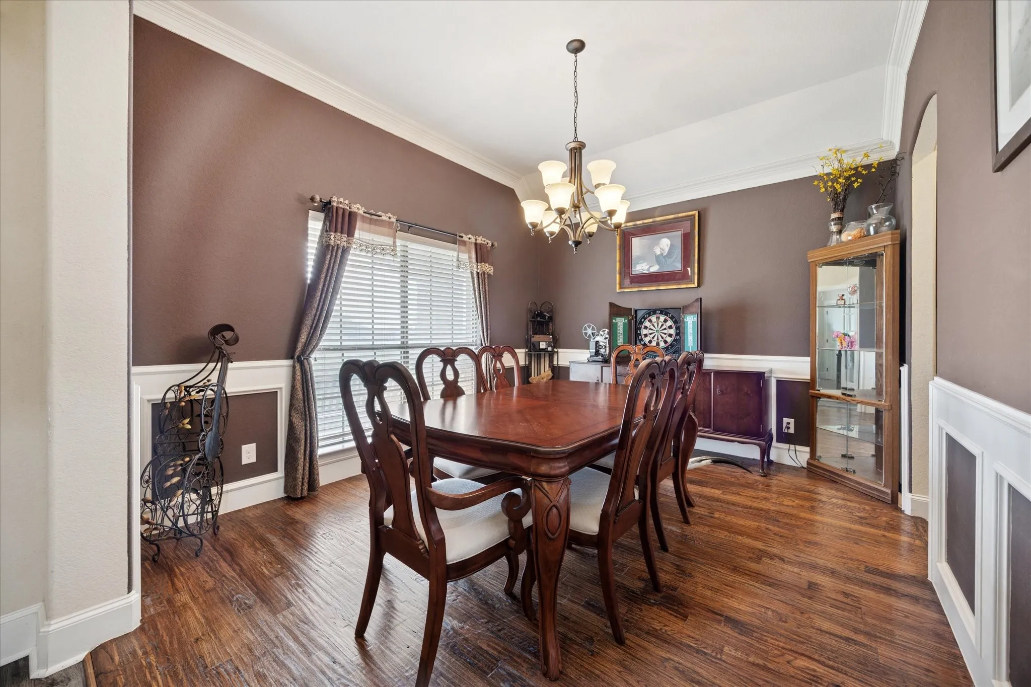 Spacious room featuring wood-finish flooring, white crown molding, and wainscoting