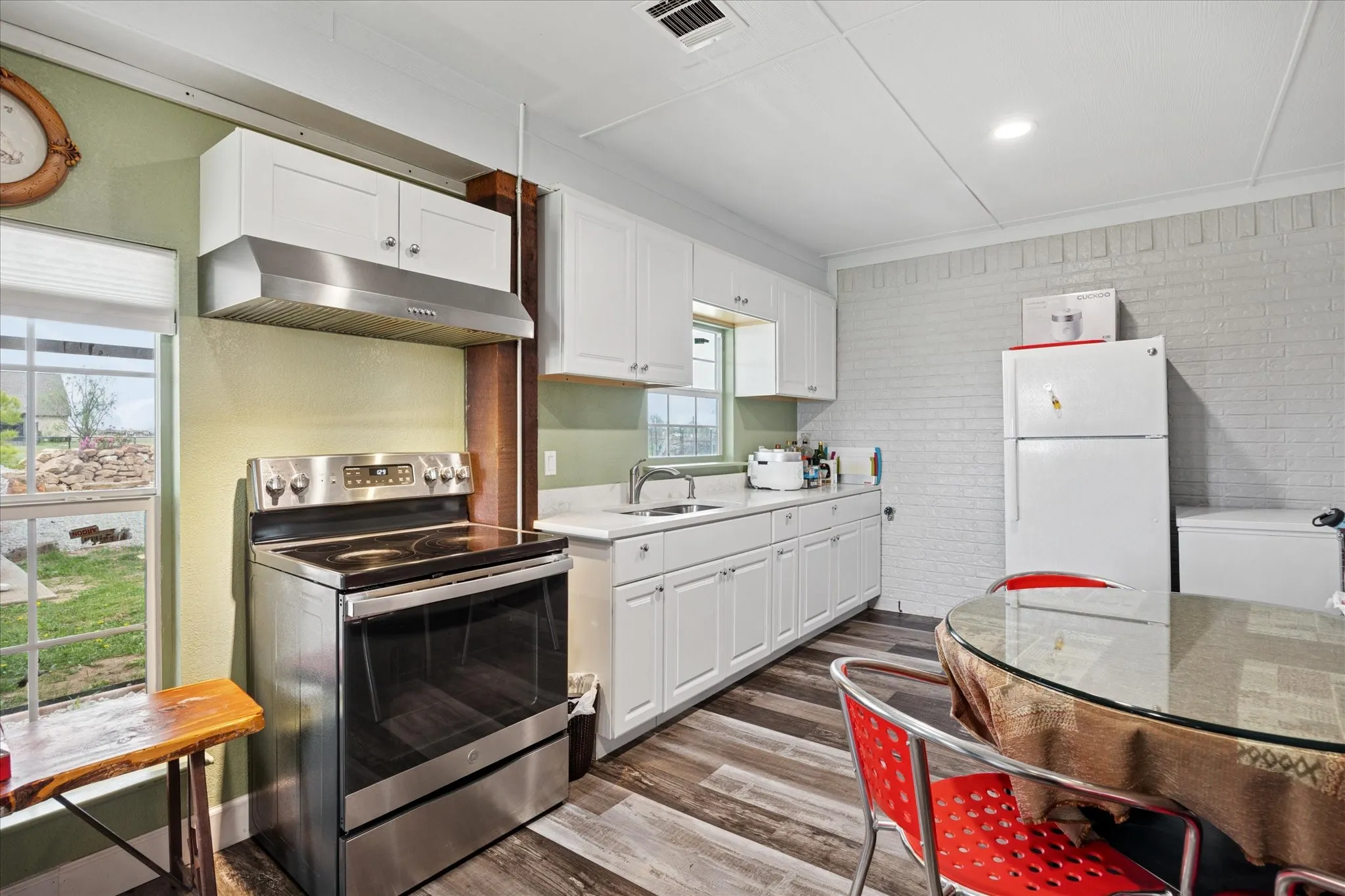 Kitchen featuring white cabinetry, wood-finish flooring, and a stainless steel electric range with an overhead vent hood