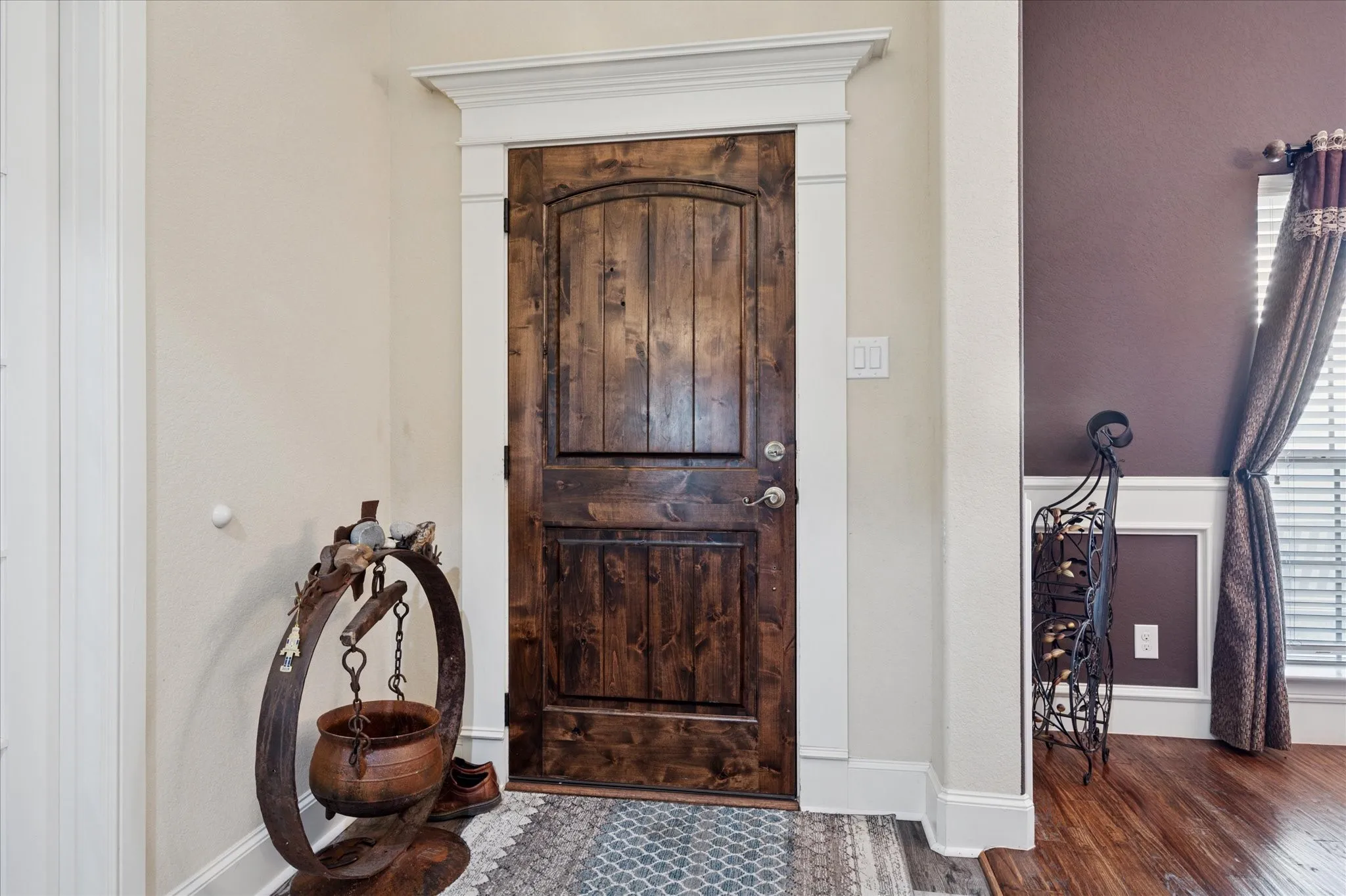 Distinguished wood-finish entry door with archtop paneling and white trim