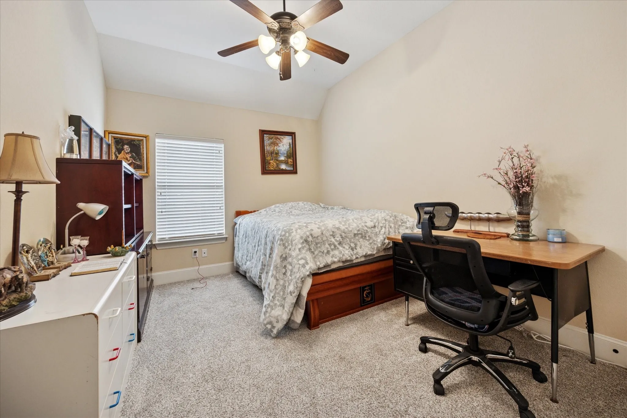 Carpeted room with a vaulted ceiling, a ceiling fan, and a single window with blinds