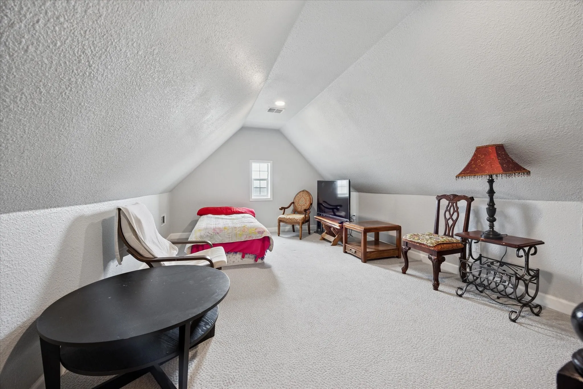 Carpeted room featuring a vaulted ceiling and a single pane window