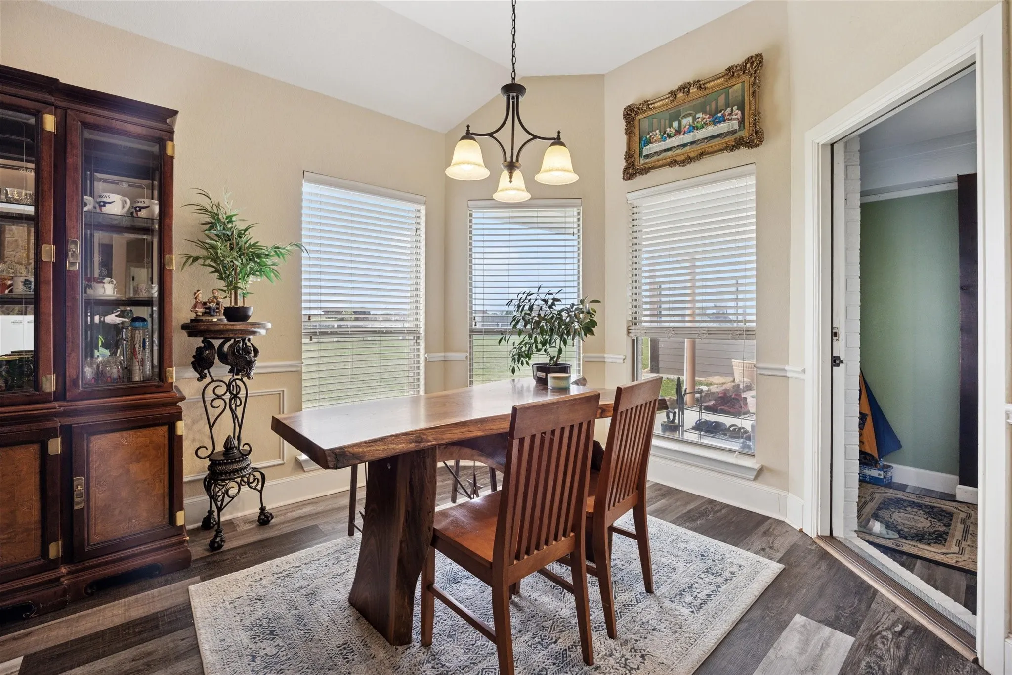 Dining area featuring wood-finish flooring, a contemporary chandelier, and multiple windows with horizontal blinds
