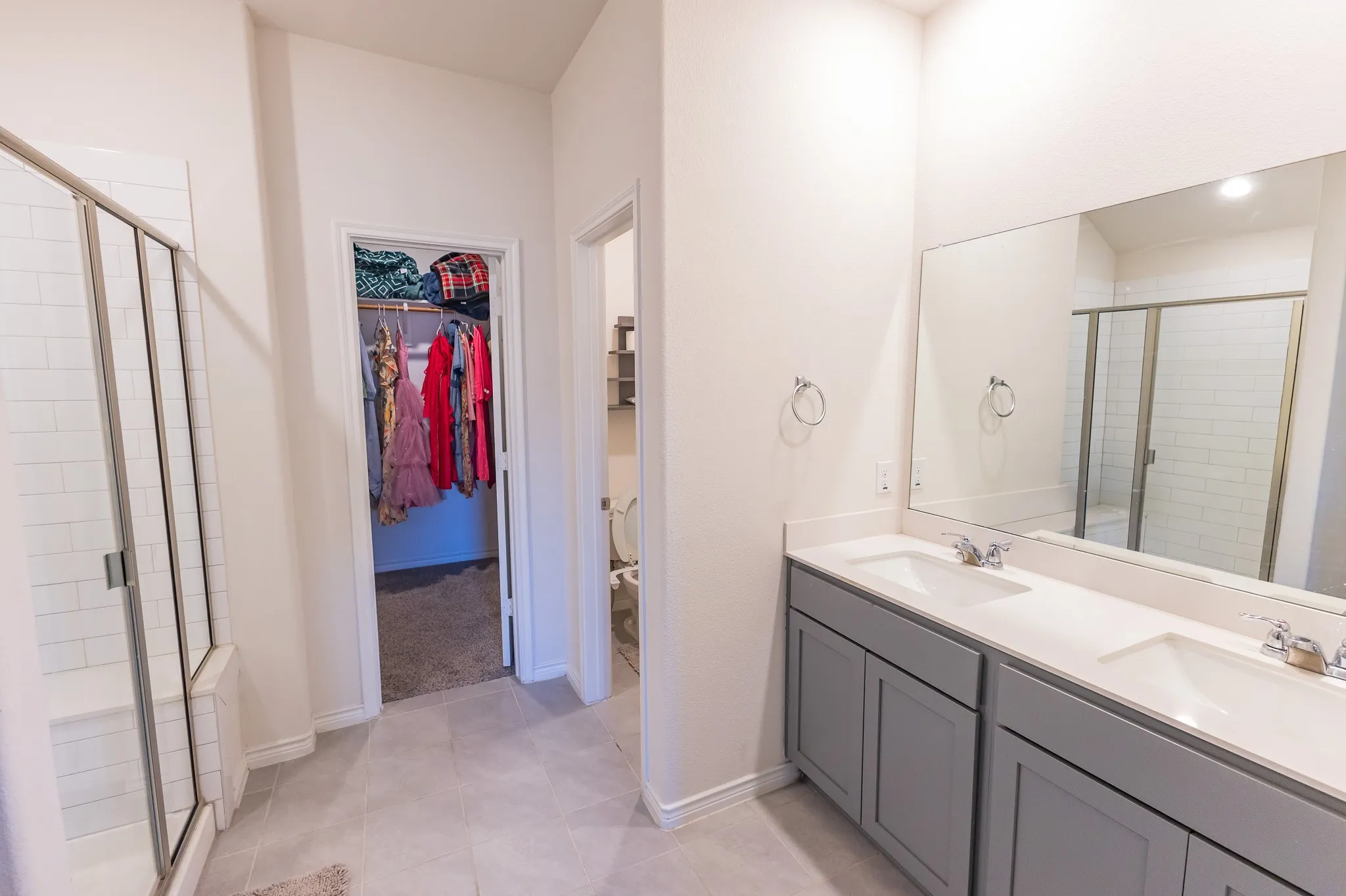 Double vanity with white undermount sinks, chrome fixtures, and grey cabinetry