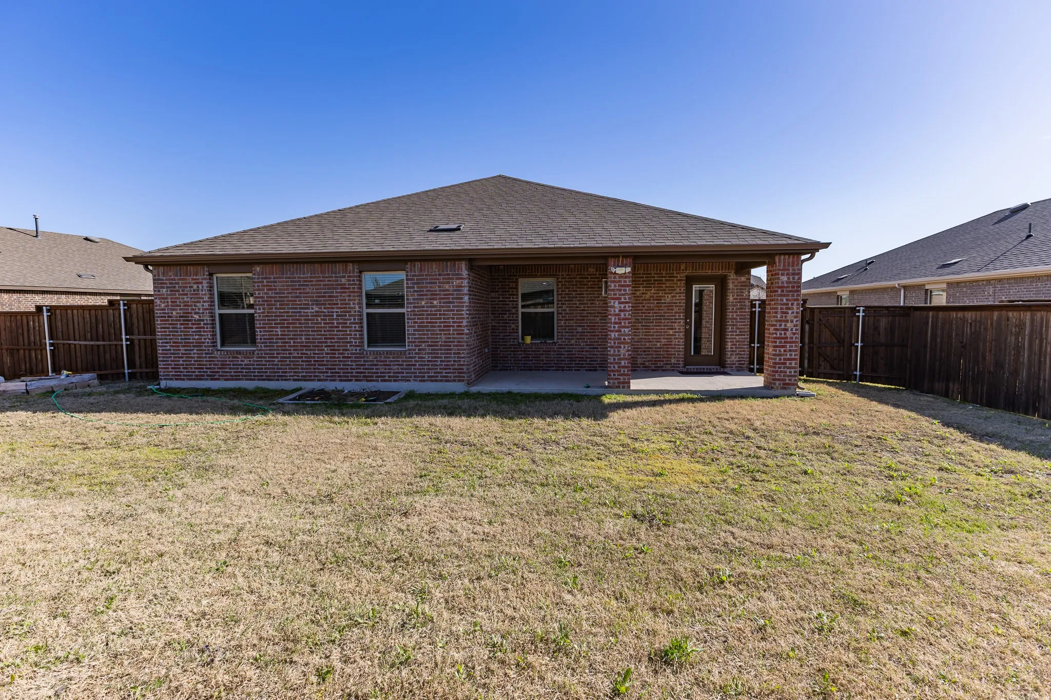 Expansive backyard featuring a brick exterior and a covered patio