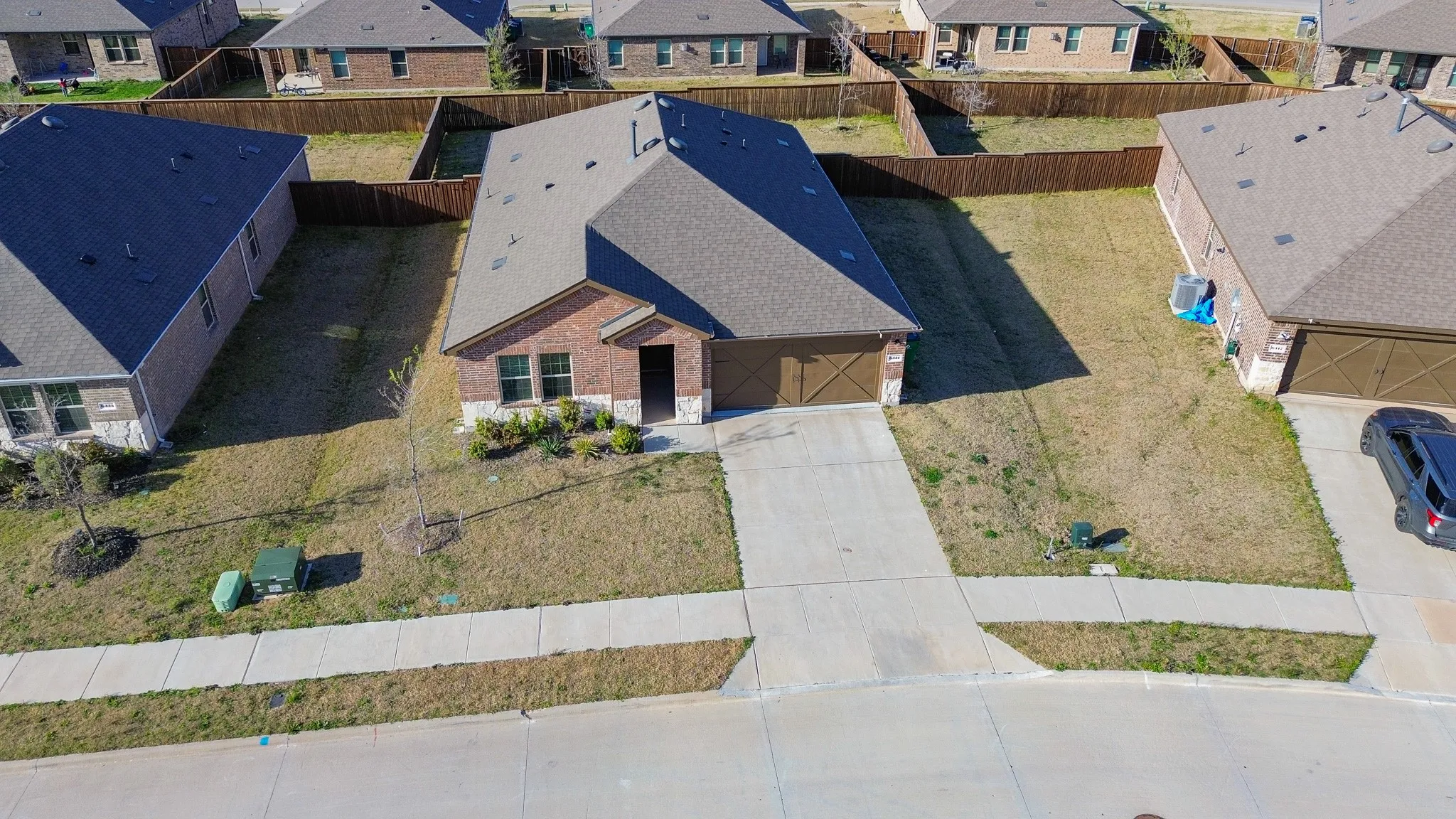 Brick and stone facade residence featuring a brown shingle roof and an attached two-car garage with cross-brace detailing
