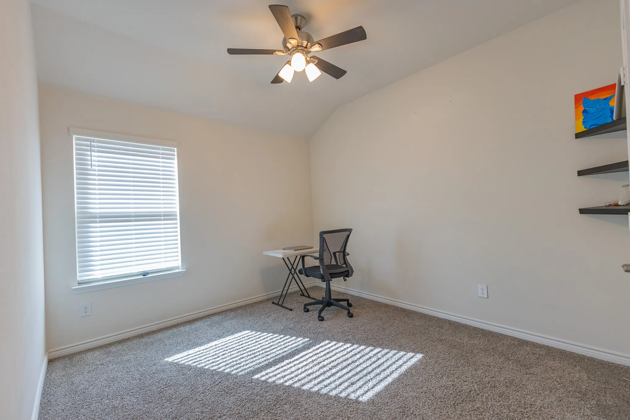 Carpeted room with a vaulted ceiling, ceiling fan with integrated lighting, and a window with horizontal blinds