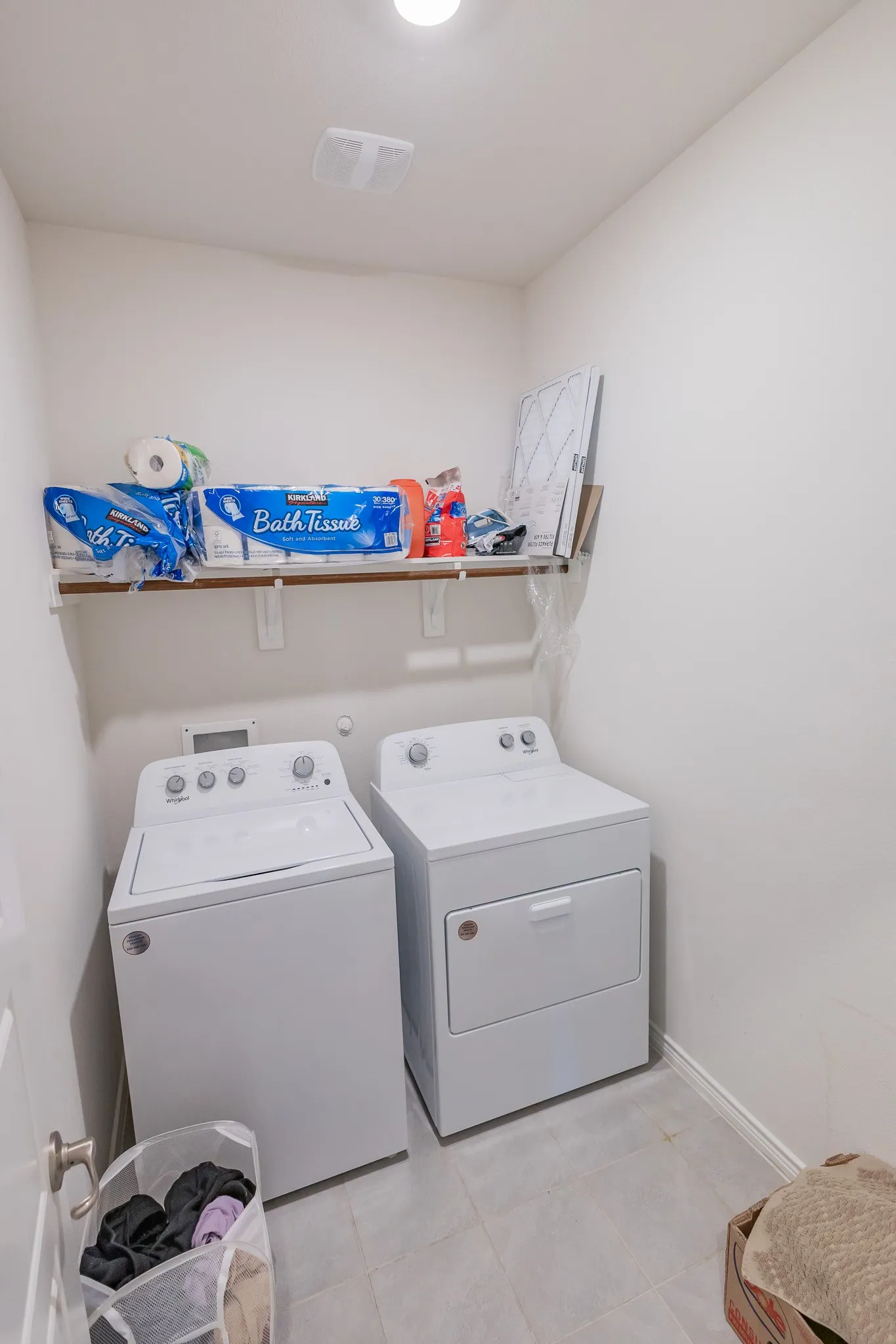 Dedicated laundry area featuring a shelf, overhead lighting, and light-toned flooring