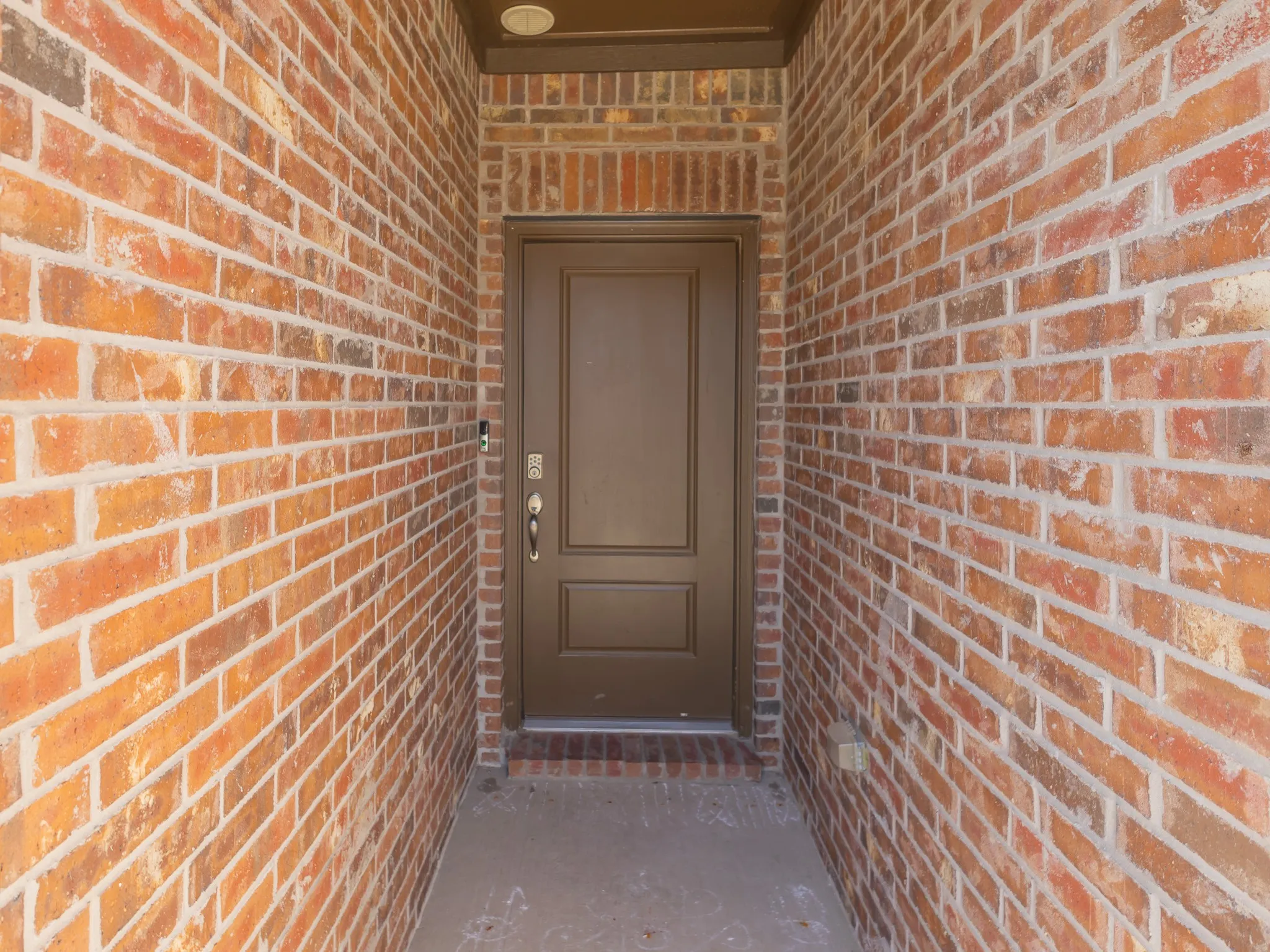 Inviting entry featuring a paneled front door, traditional brick facade, and recessed lighting