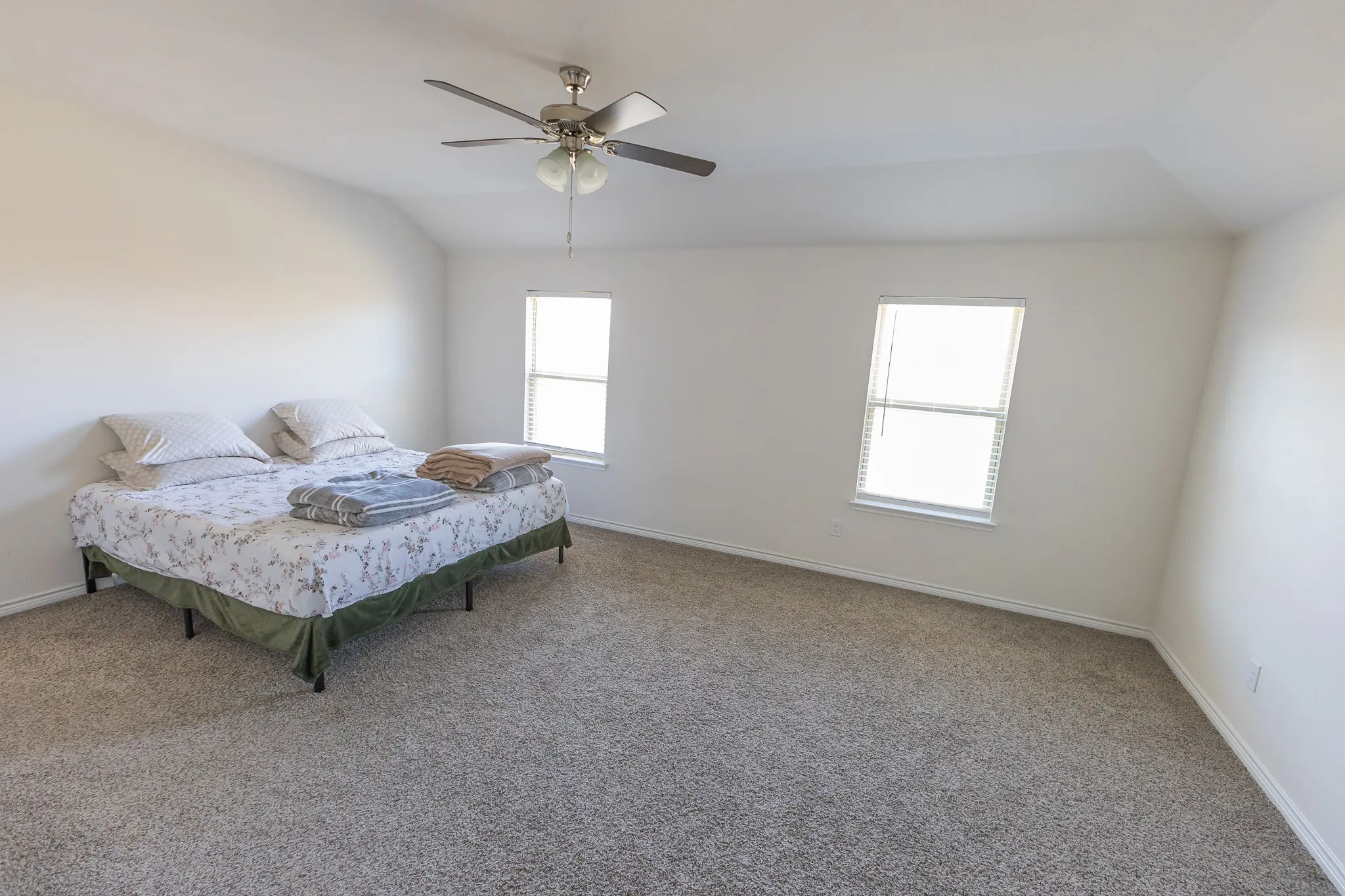 Carpeted room with vaulted ceiling and two windows