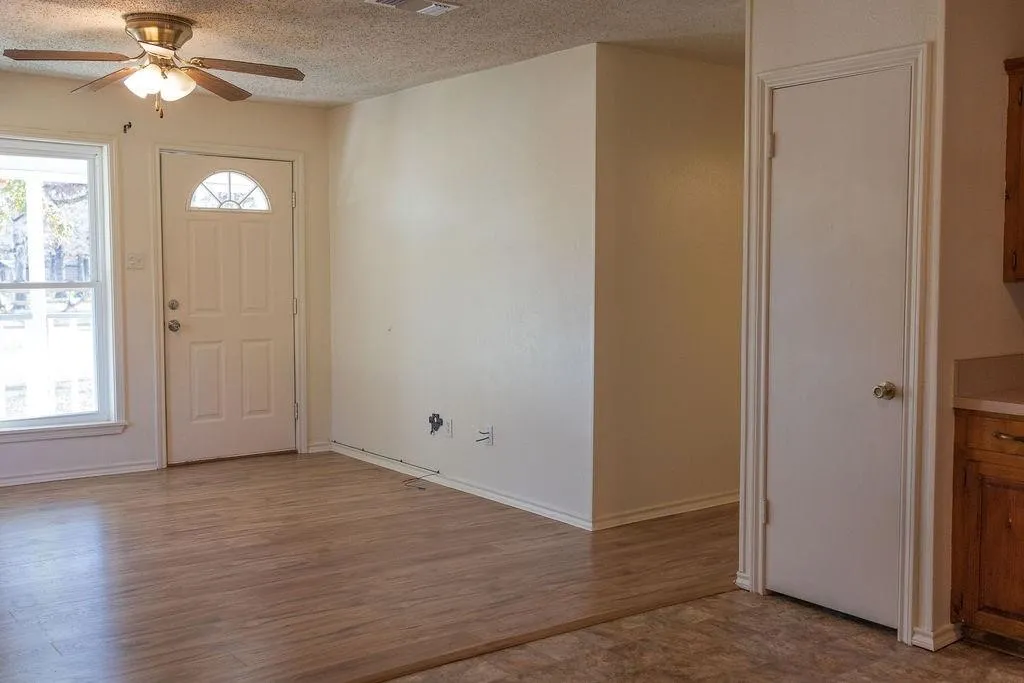 Entry area featuring wood-finish flooring and a white paneled door with a decorative glass insert