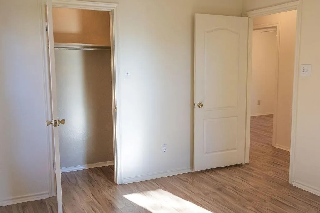 Room with light-toned walls, wood-finish flooring, and white baseboards