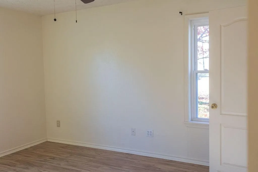 Room featuring light-toned walls, wood-finish flooring, and white trim