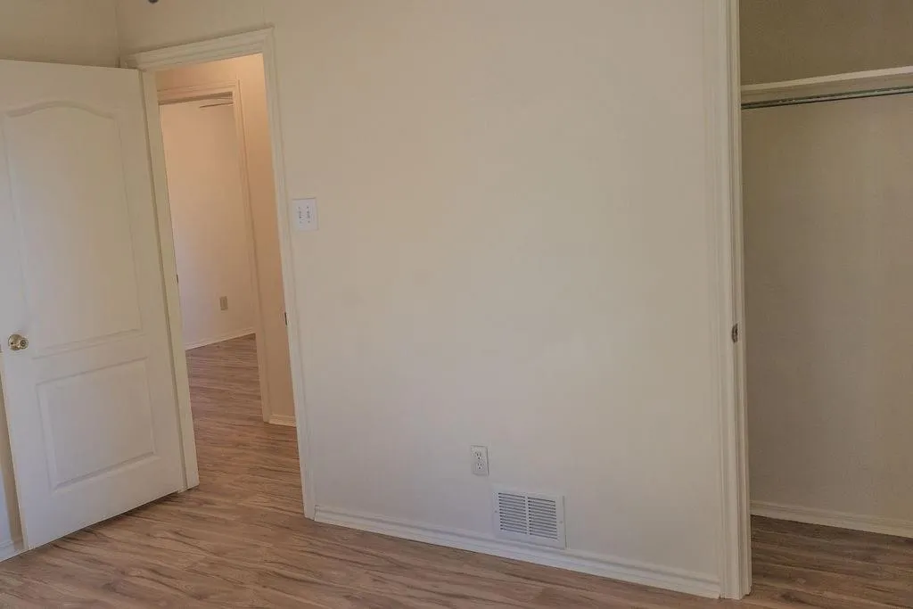 Interior room featuring wood-finish flooring, light neutral wall paint, and white baseboards