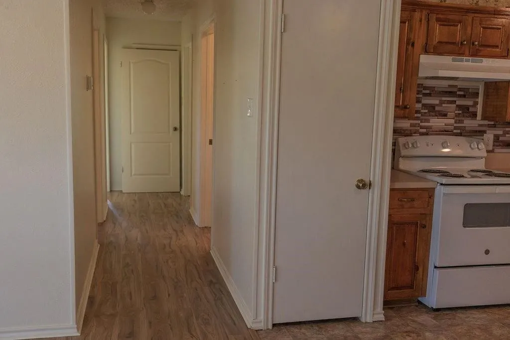 Hallway with wood-finish flooring, white walls, and white trim
