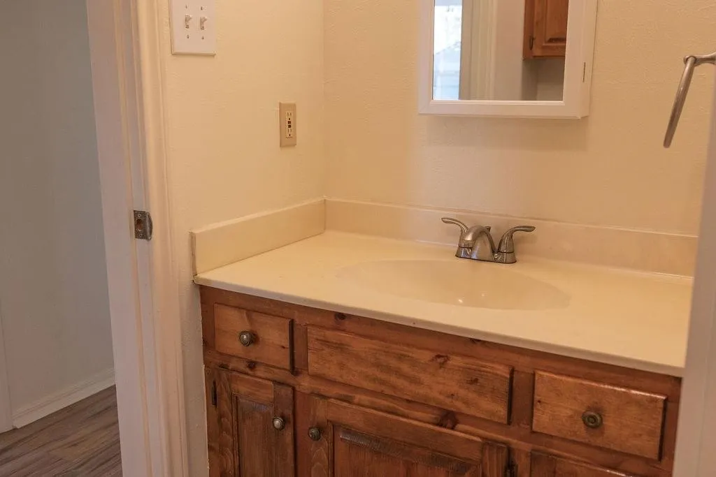 Bathroom vanity with a built-in sink, wood-finish cabinetry, and a mirrored medicine cabinet