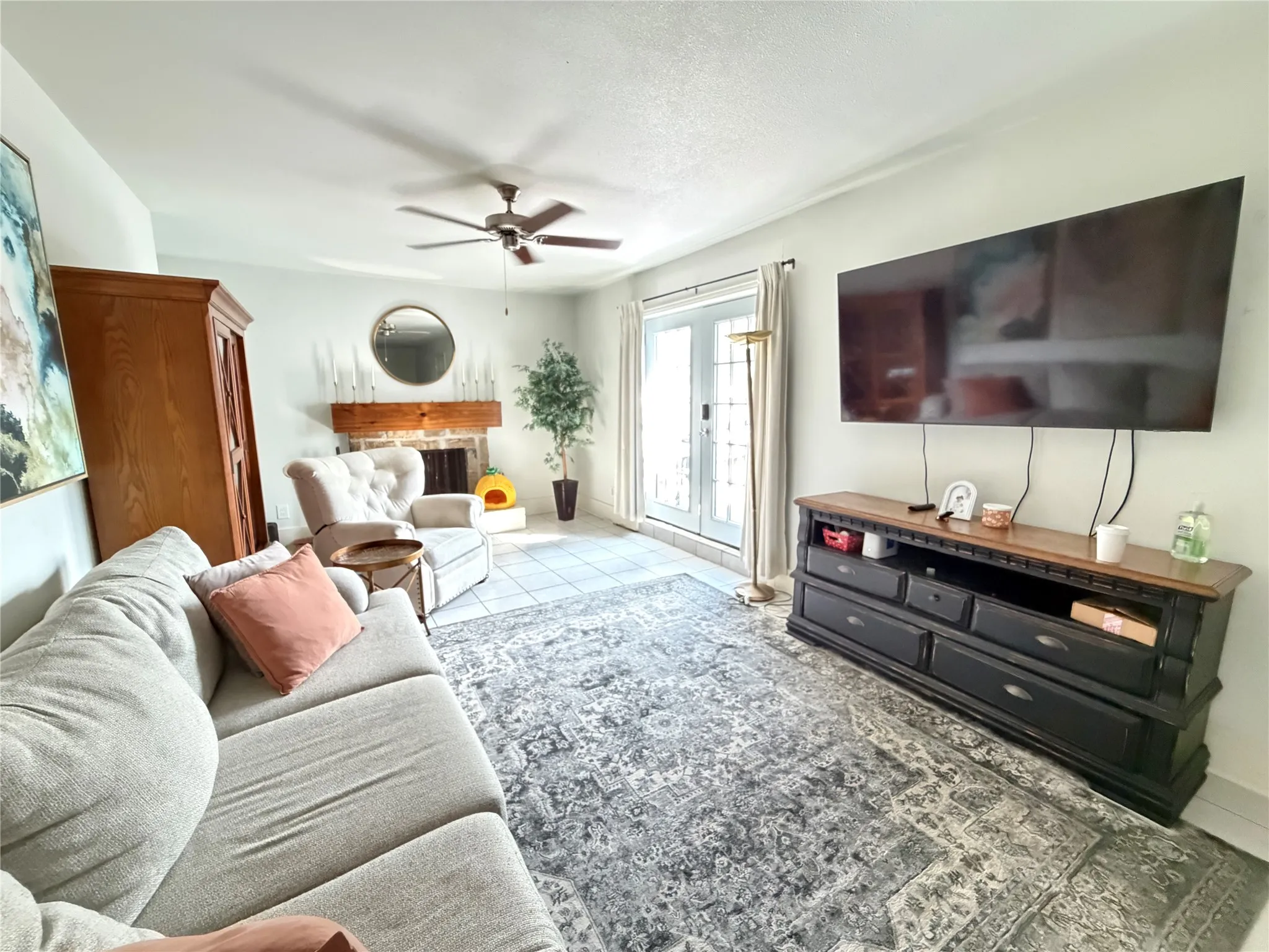 Living area featuring tile flooring, a fireplace with a wood mantel, and French doors