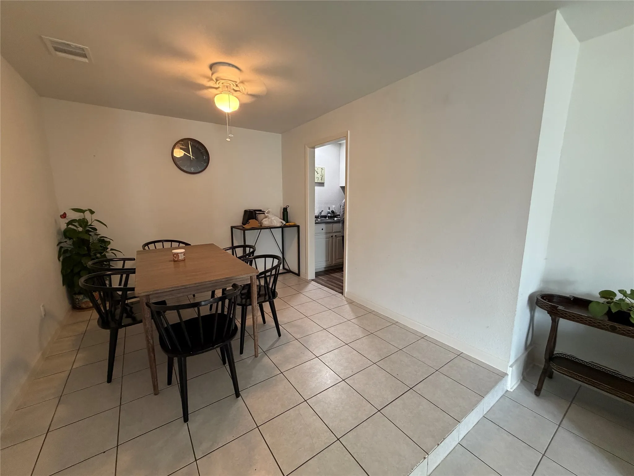 Dining area featuring neutral tile flooring, a ceiling fan with integrated lighting, and a doorway opening to an additional room
