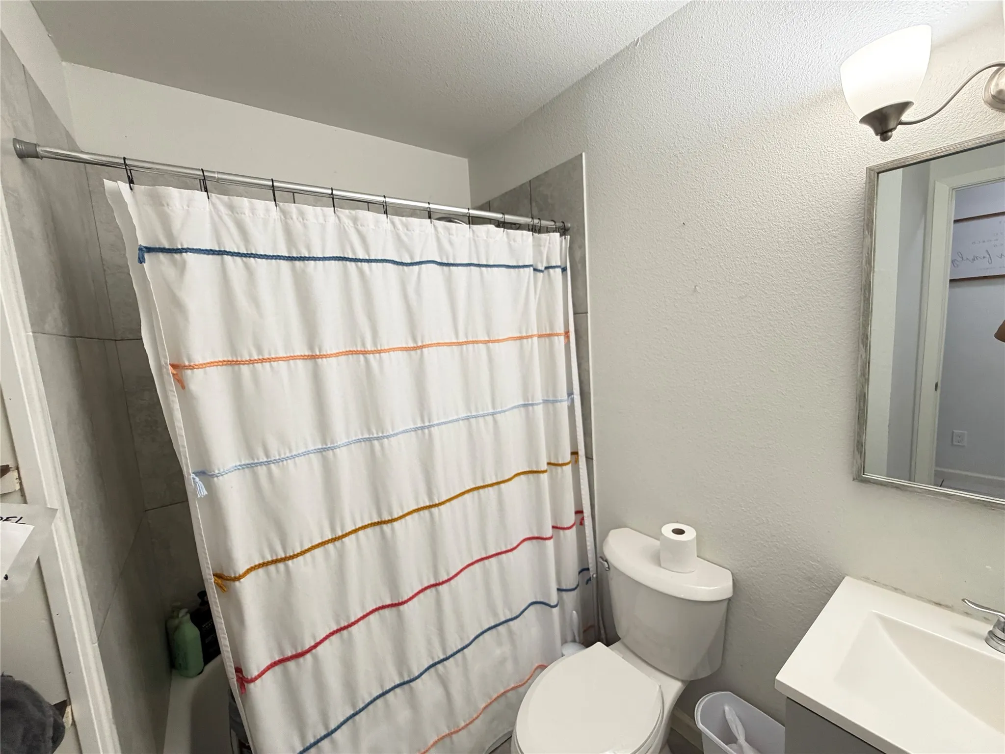 Bathroom featuring a ceramic tile shower surround, a white toilet, and a vanity with an integrated sink