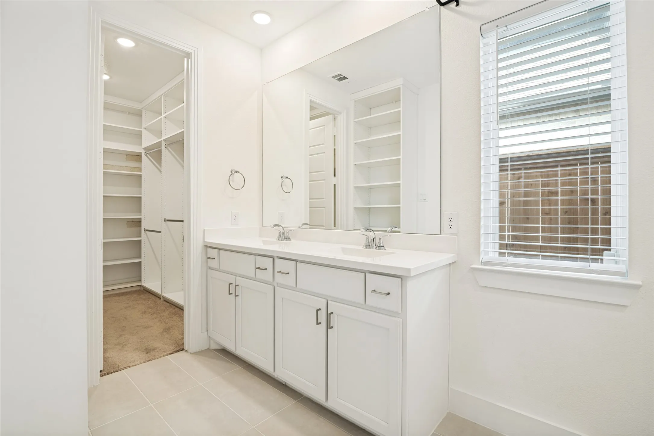 Bathroom featuring a dual vanity with white cabinetry, a large vanity mirror, and recessed lighting